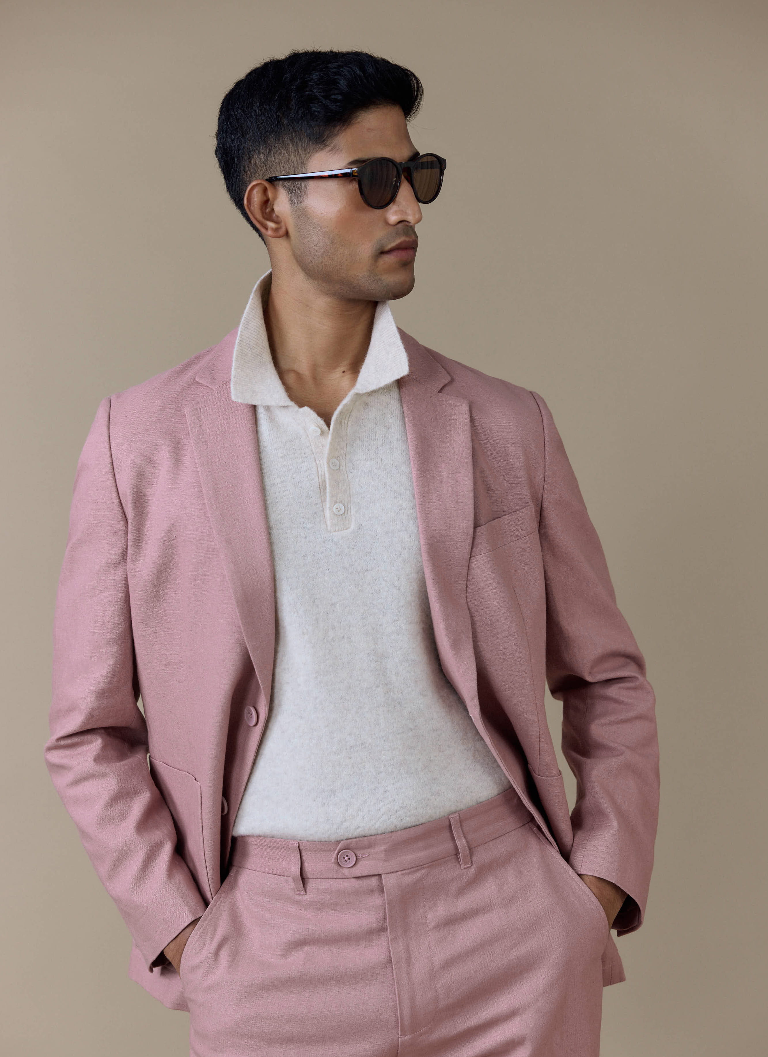 Tailored Dusty Pink linen blazer by Percival, worn by a model with matching trousers and a cream knitted polo.