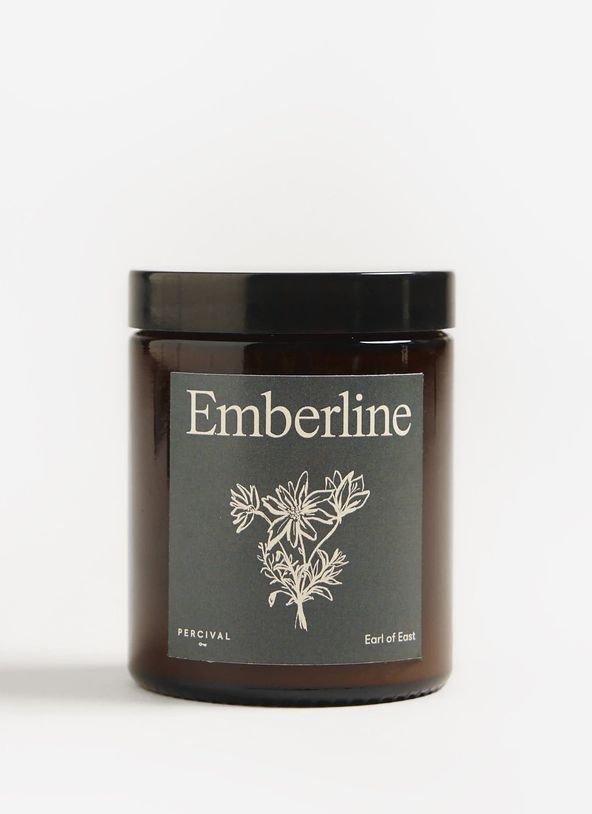 The Percival x Earl of East Emberline candle in an amber glass jar with a black lid and illustrated label.