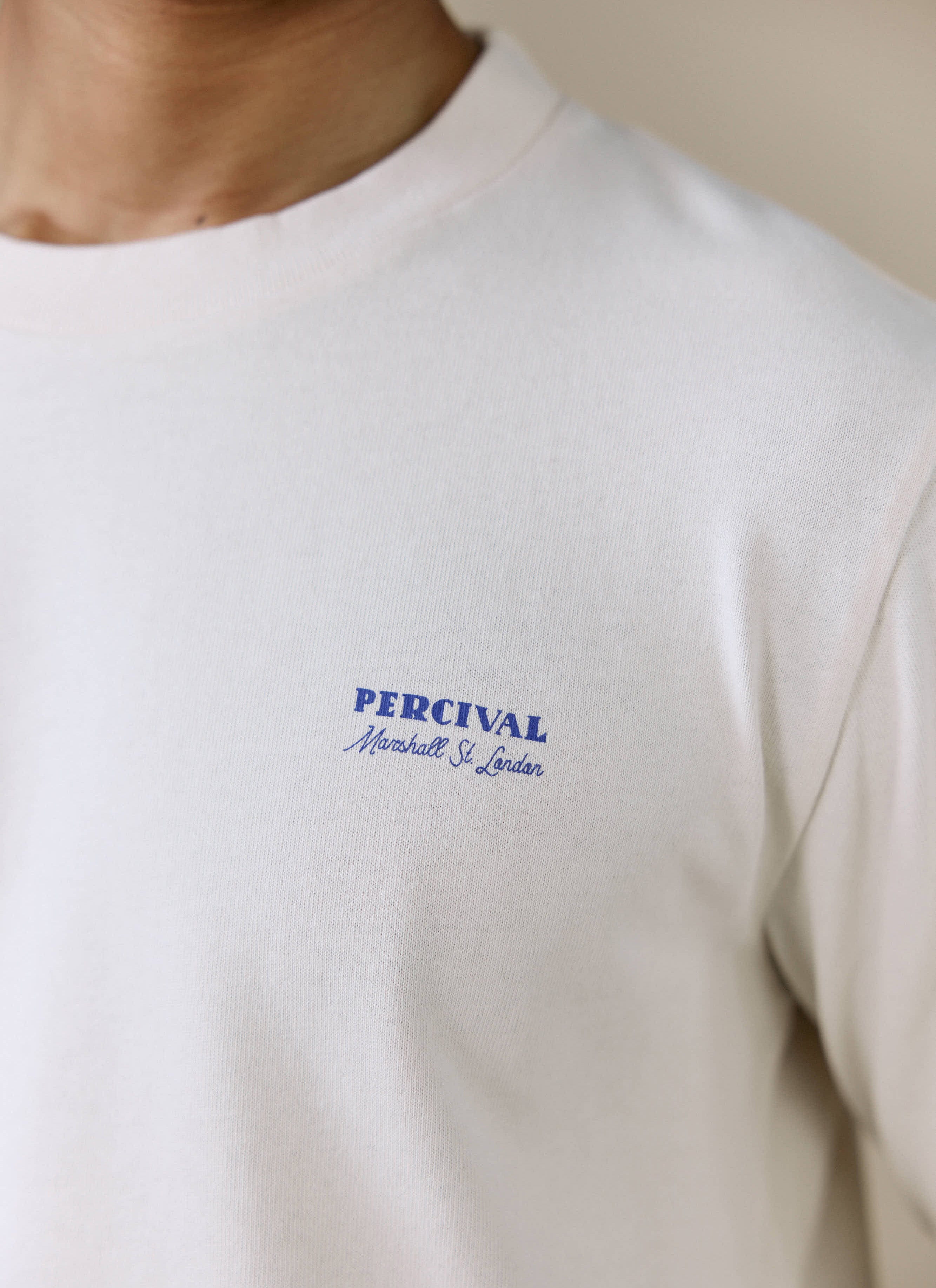 A close-up of the blue Percival Marshall St. London graphic on the chest of the cream Harlow Fine Wines long sleeve T shirt.