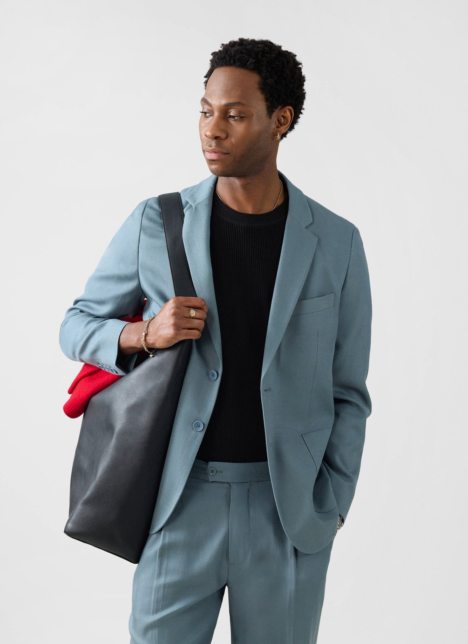A model wears the Percival Lyocell Regular Blazer in slate blue, styled over a black top and carrying a large black tote bag.