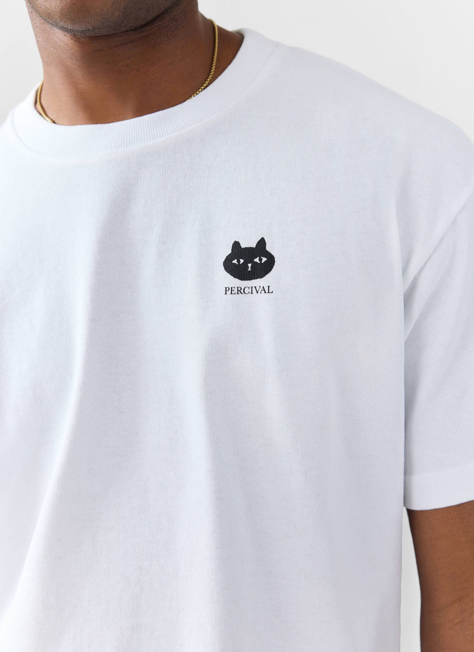 Close up of a model wearing the Percival Perci Loaf oversized t-shirt in white, showing the black cat graphic on the chest.