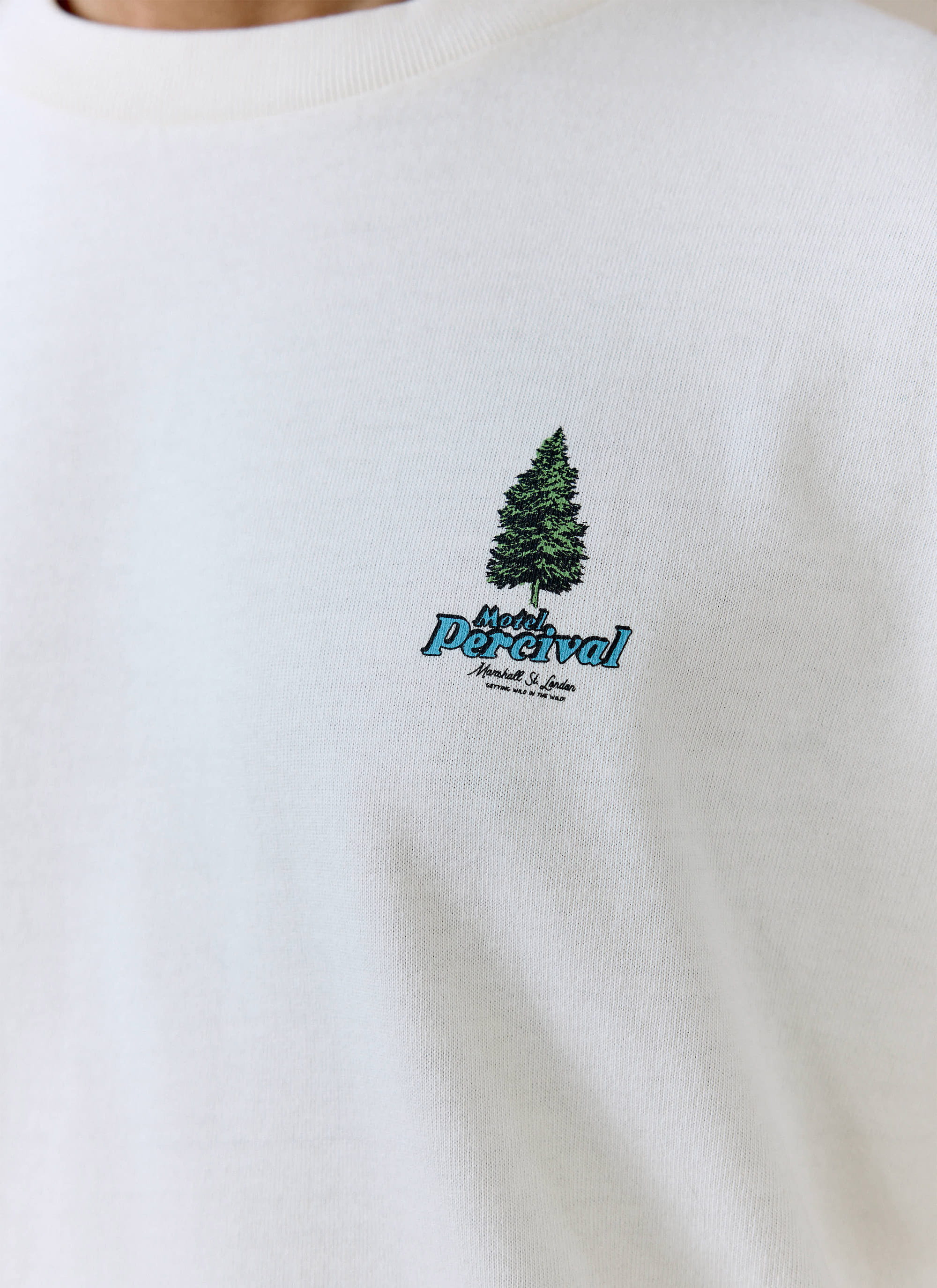 Close-up of the blue Motel Percival graphic and pine tree on the cream organic cotton Arnold Oversized T Shirt.