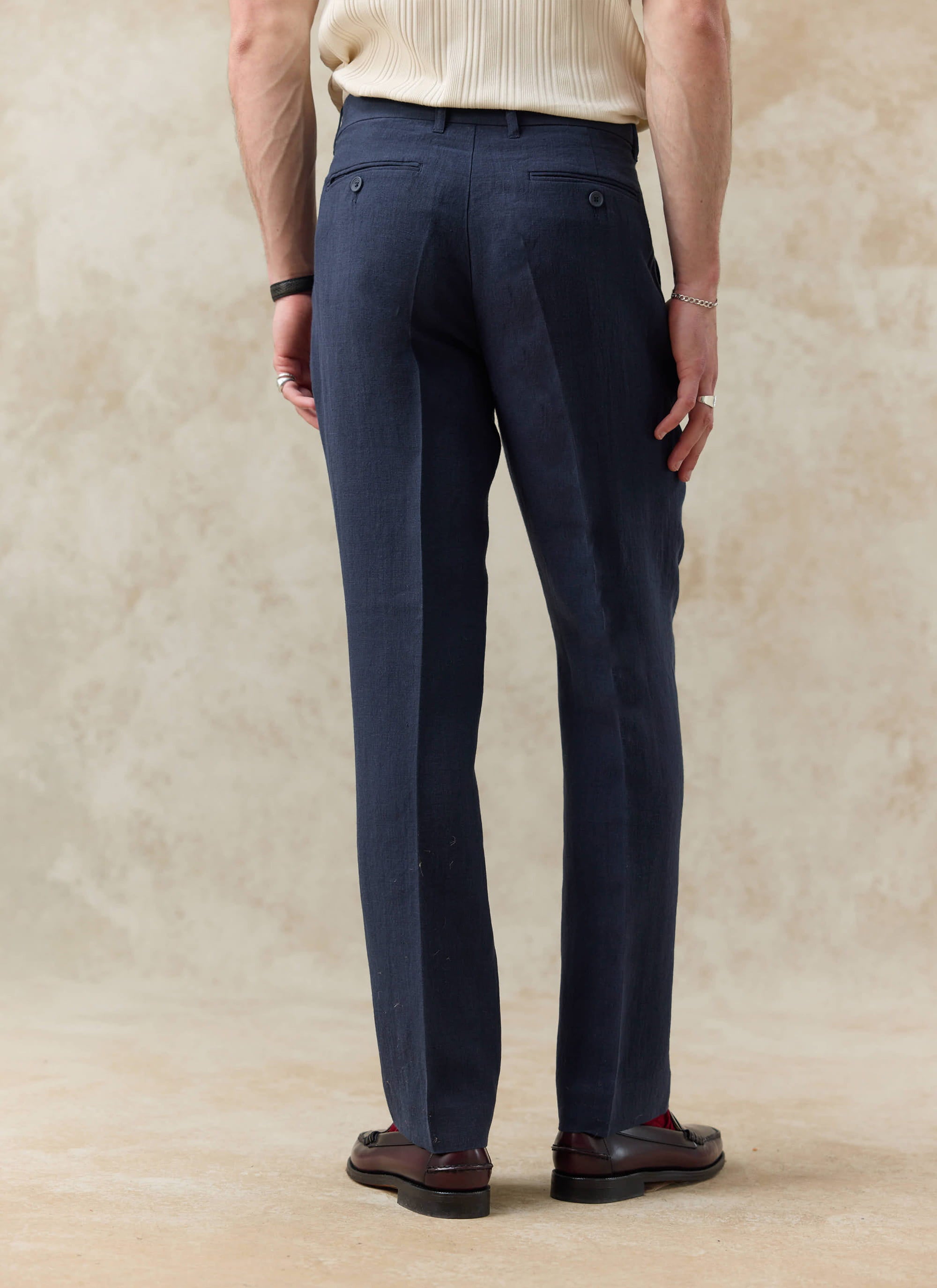 Rear view of navy blue tailored linen trousers by Percival, featuring a straight leg fit and textured linen finish.
