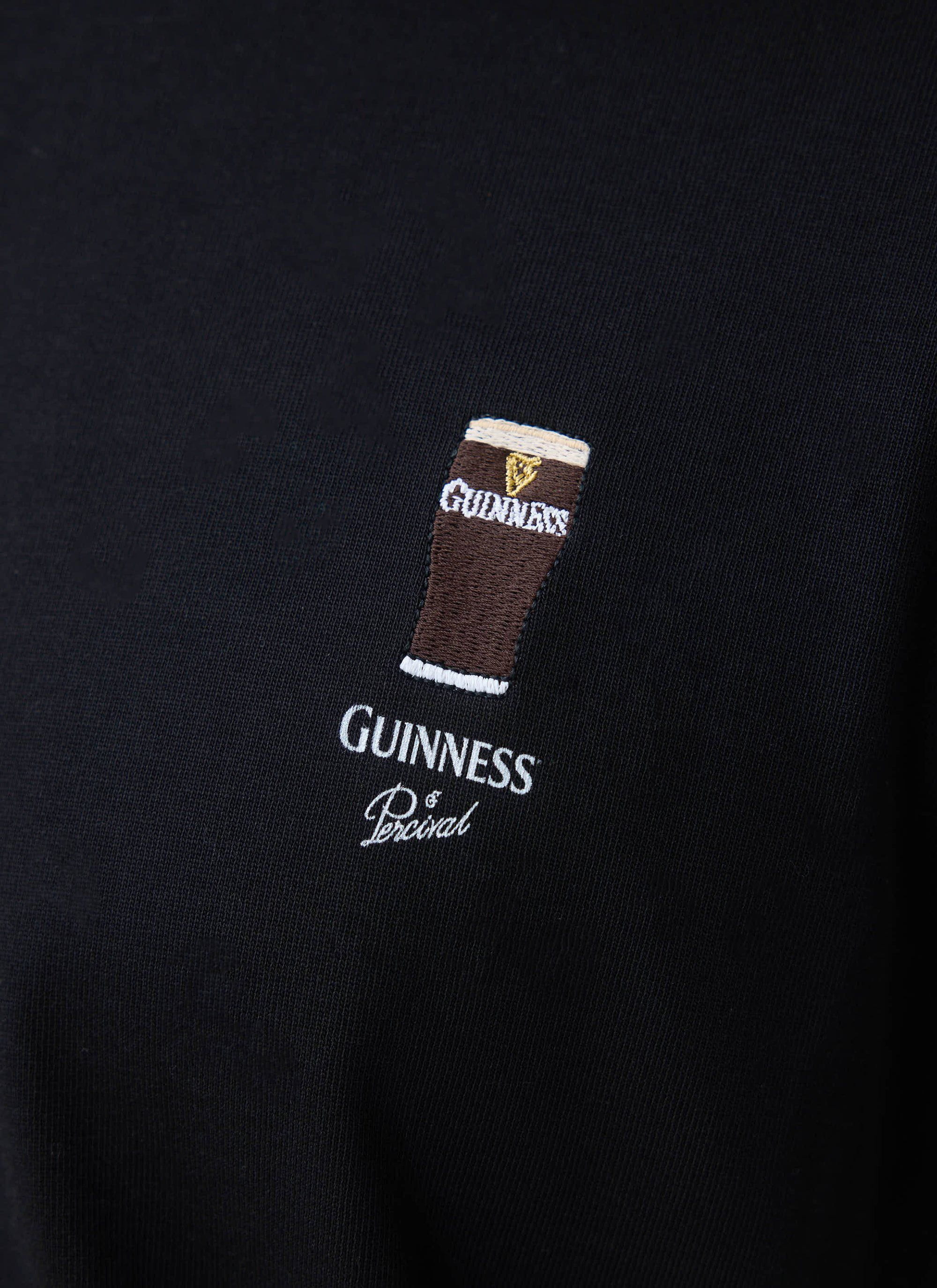 A close-up of the Percival x Guinness Stout T-shirt in black, showing the detailed embroidery of a Guinness pint.