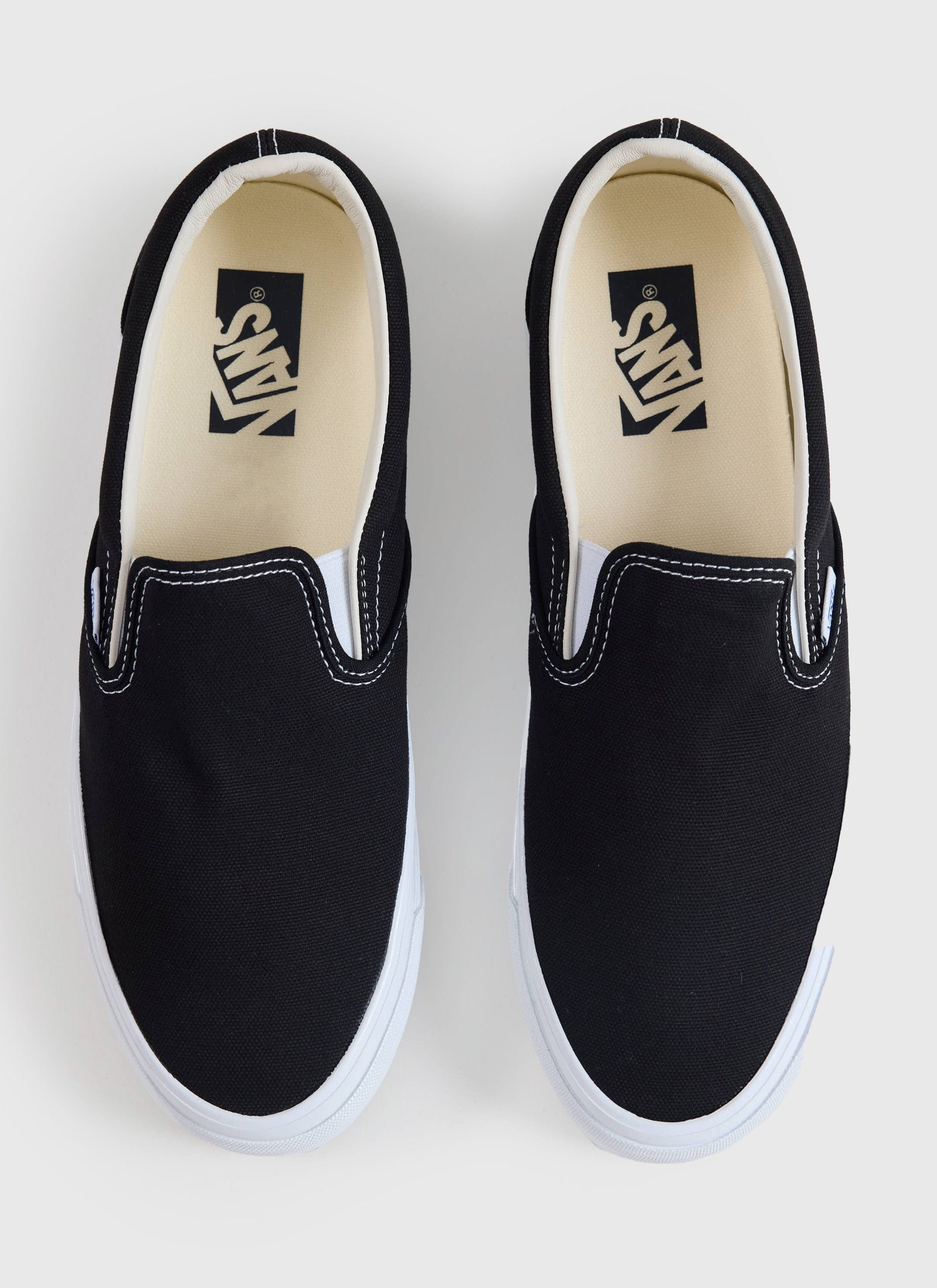 Top-down view of the Vans Slip-On Reissue 98 in black canvas from Percival, featuring white contrast stitching and soles.