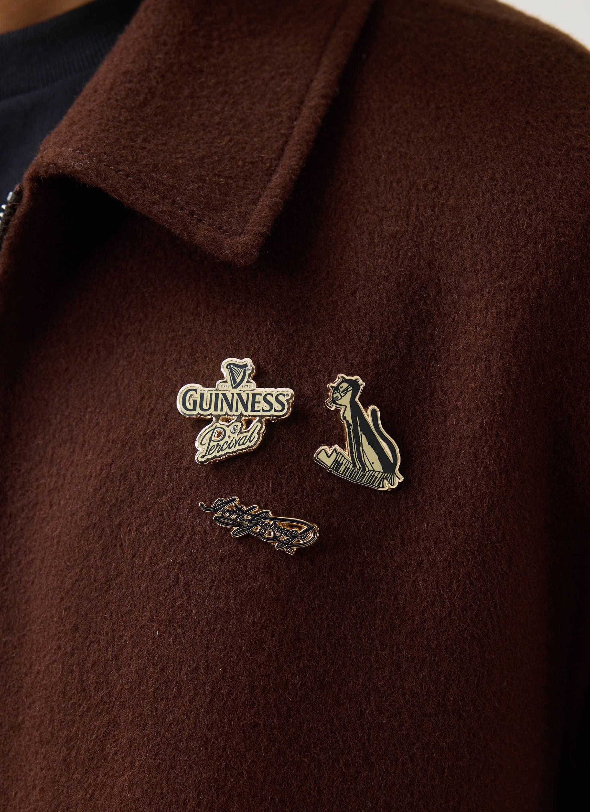 Close up of the Guinness x Percival pin badges on the lapel of the espresso brown wool jacket from Percival.