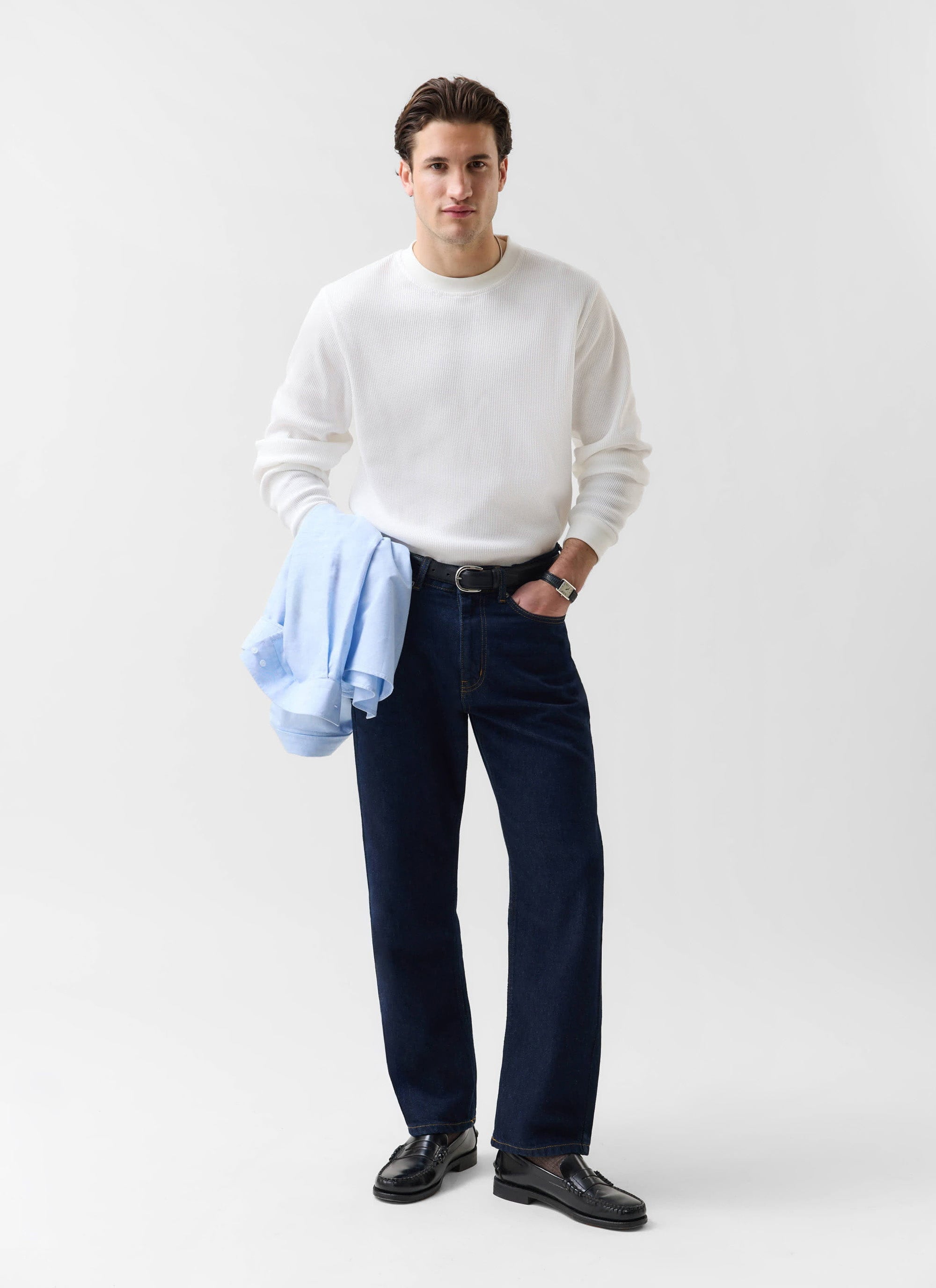 A model wears the Percival Waffle Long Sleeve T Shirt in white, styled with dark denim jeans and black loafers.