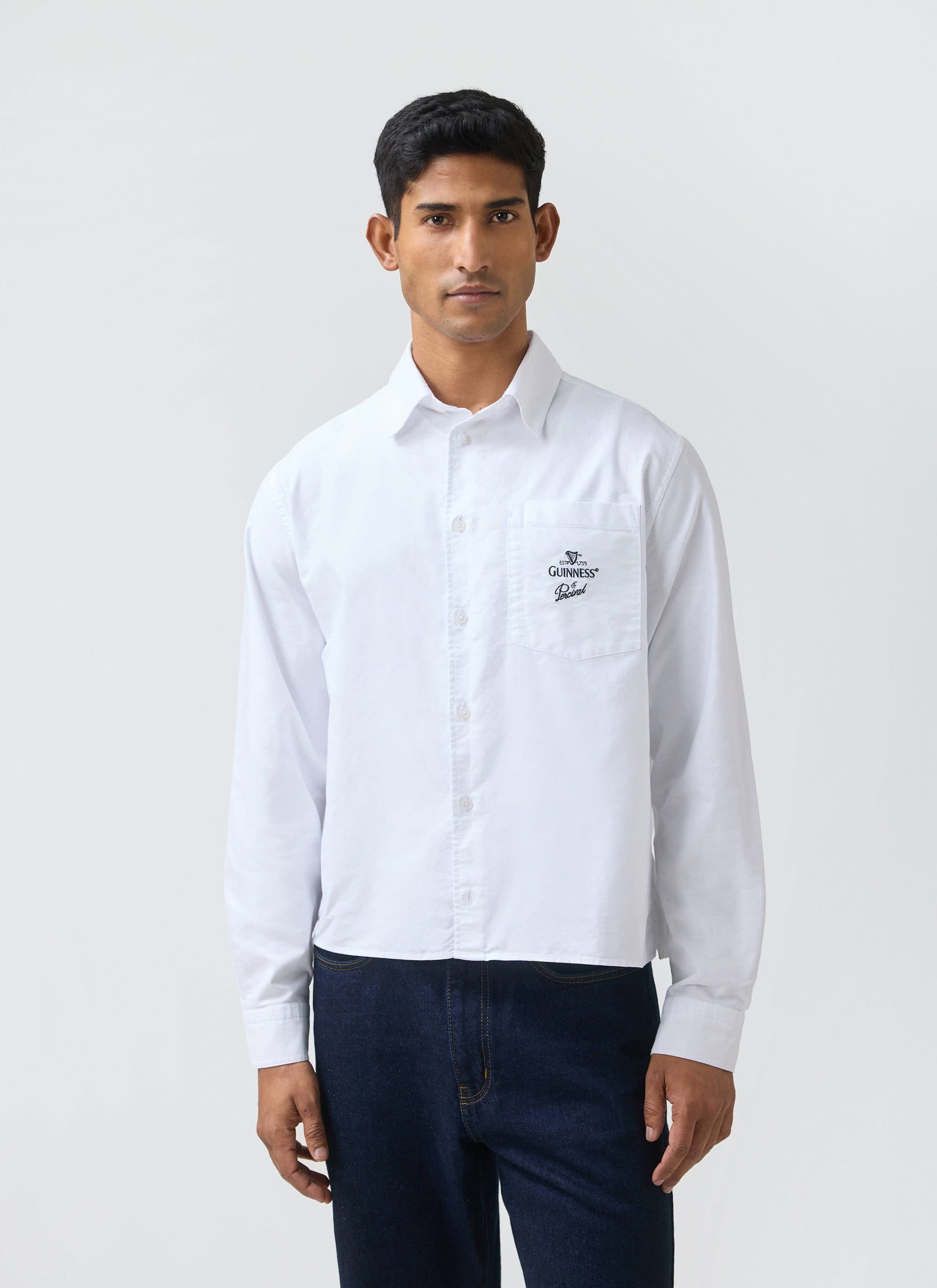 A model wears the white Button Down Boxy Shirt from the Guinness x Percival collection against a plain background.