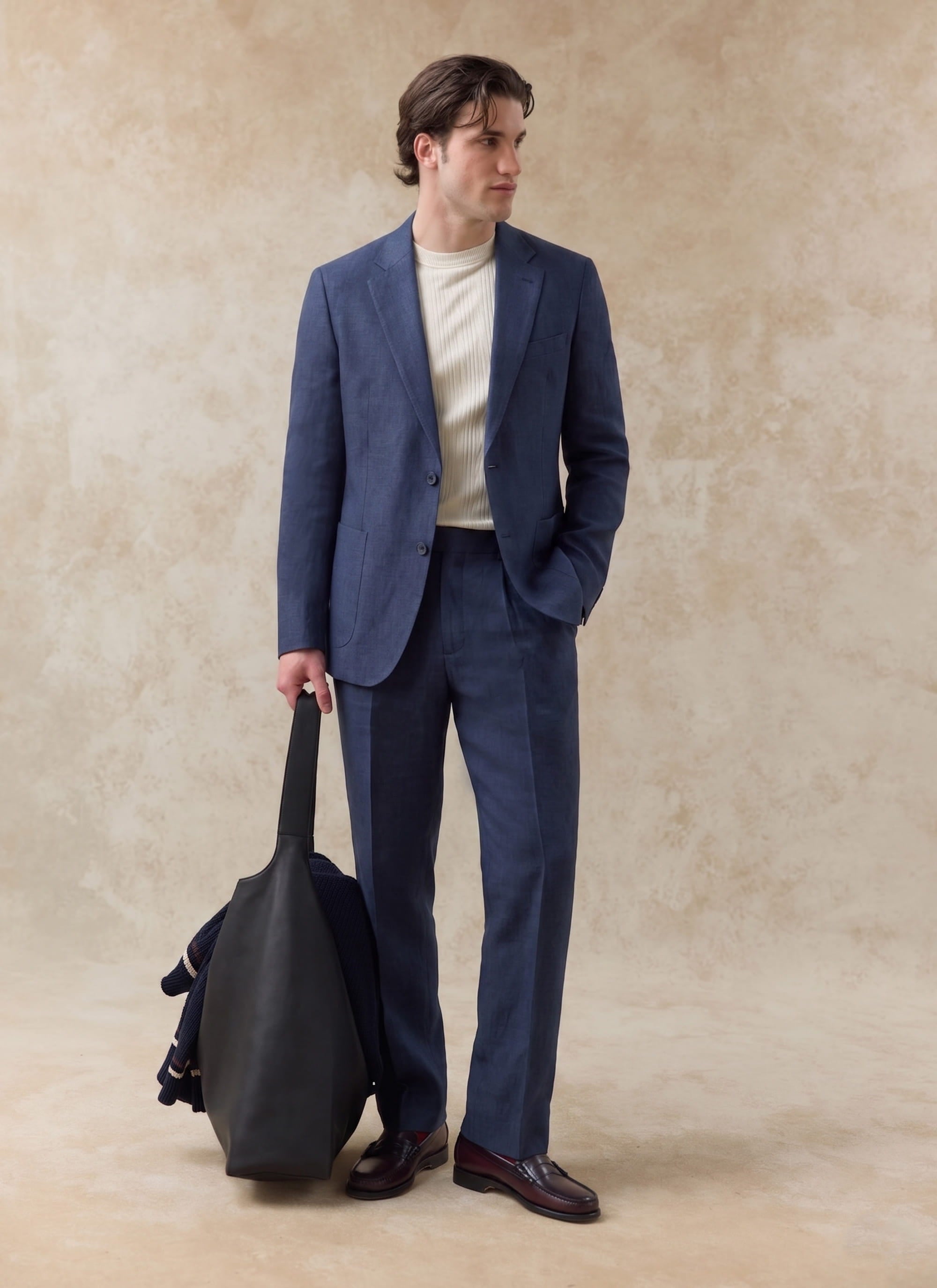 Navy tailored linen trousers and matching blazer by Percival, styled with a cream knit top and black bag.