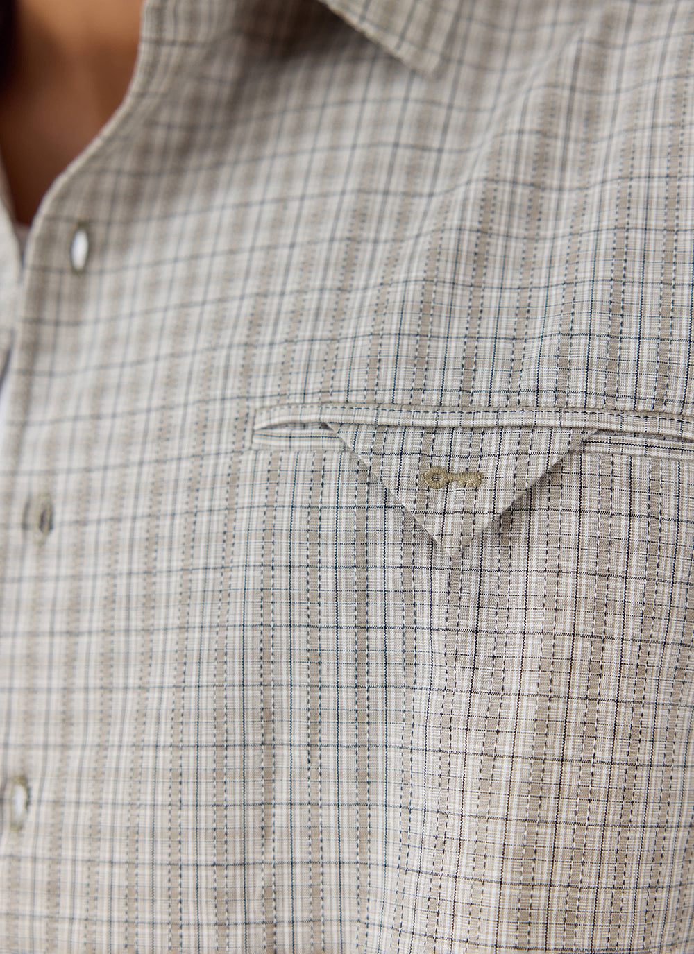 Close-up of the cream check Hinsley Boxy Shirt from Percival, featuring a chest pocket with small key embroidery.