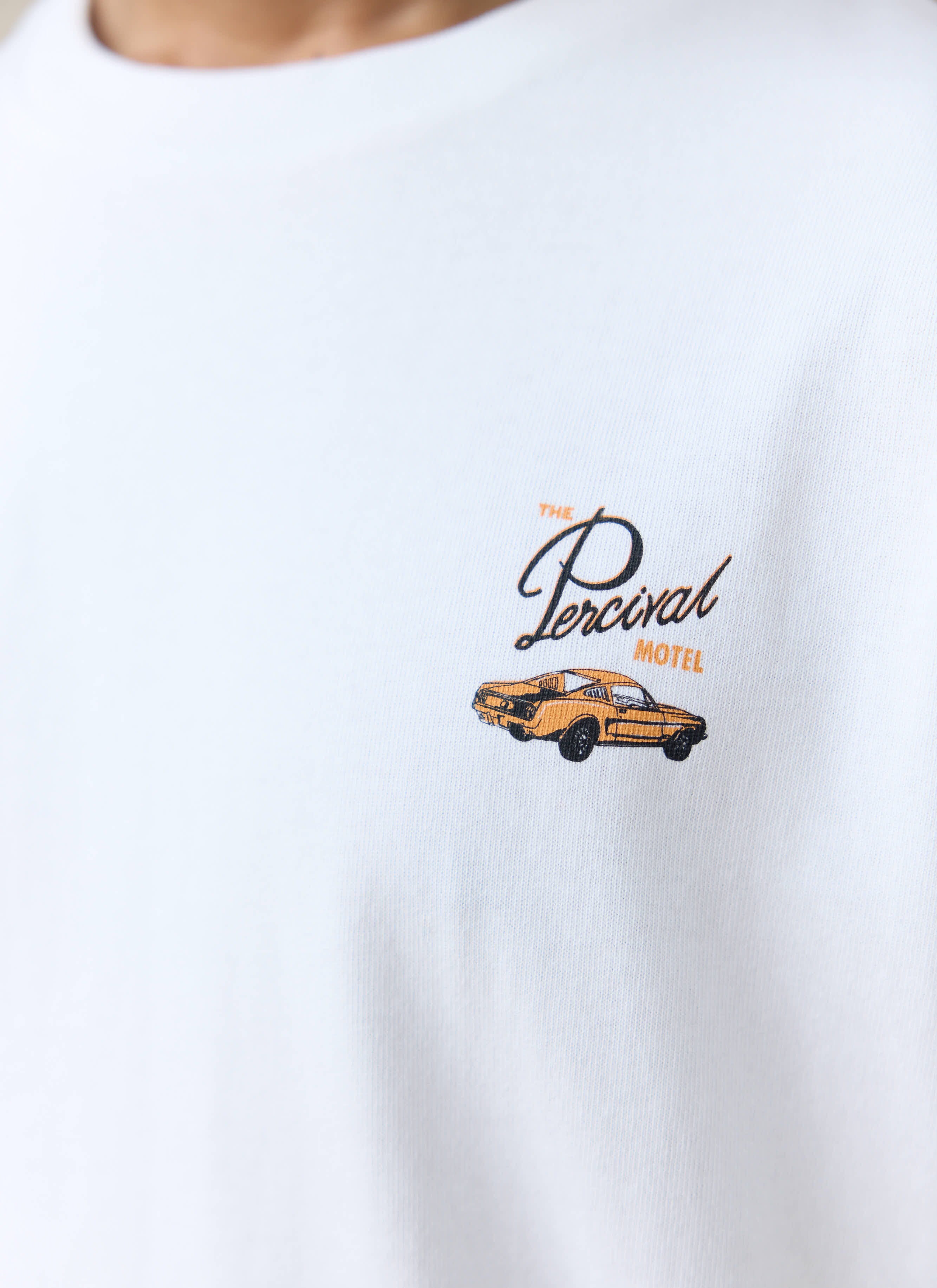 Close-up of the white organic cotton Percival Alistair T-shirt, showing The Percival Motel chest graphic and orange car.