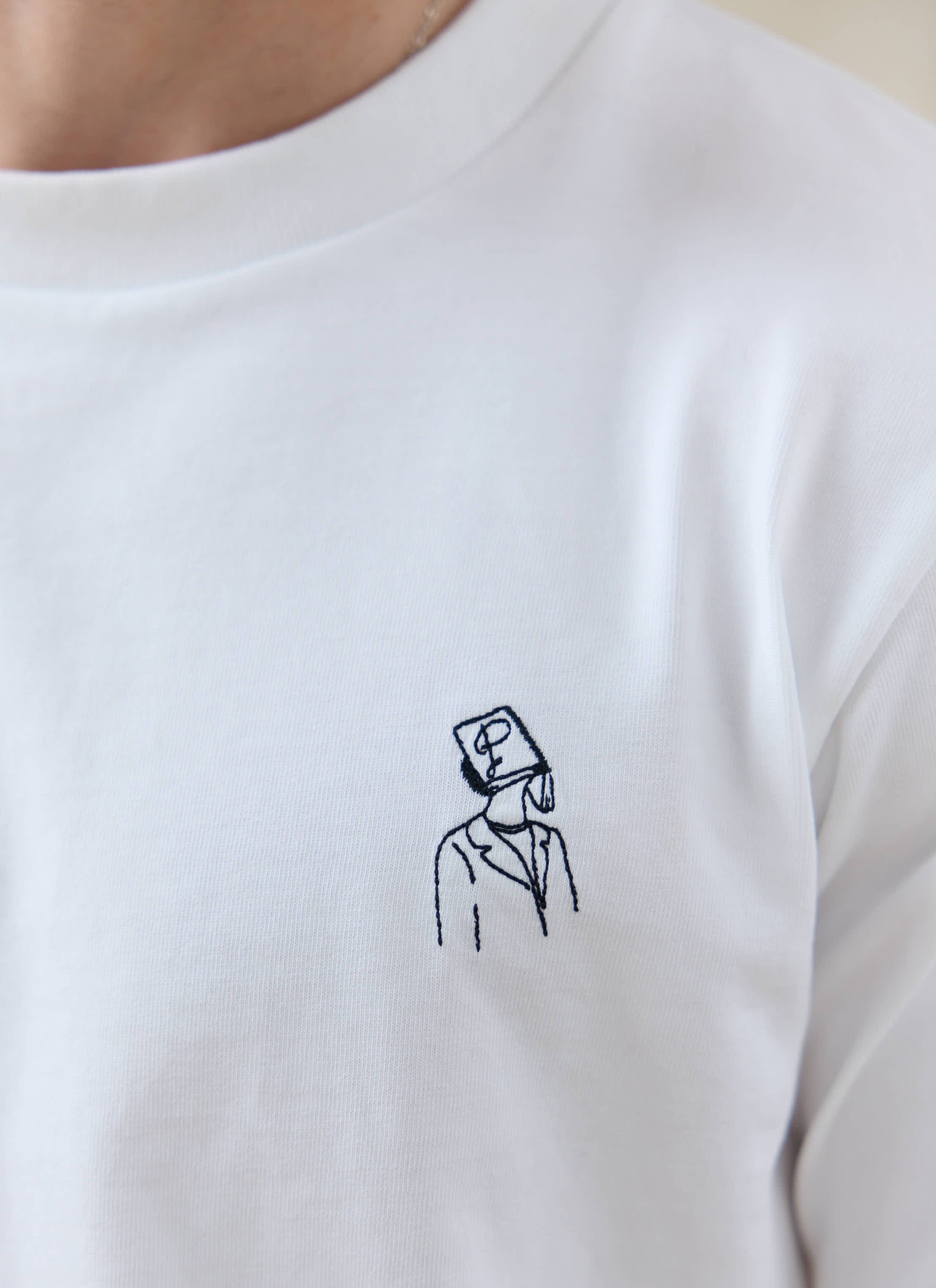 Close-up of the white Percival Robinson organic cotton t-shirt with embroidery; want more? check out the SS26 collection.