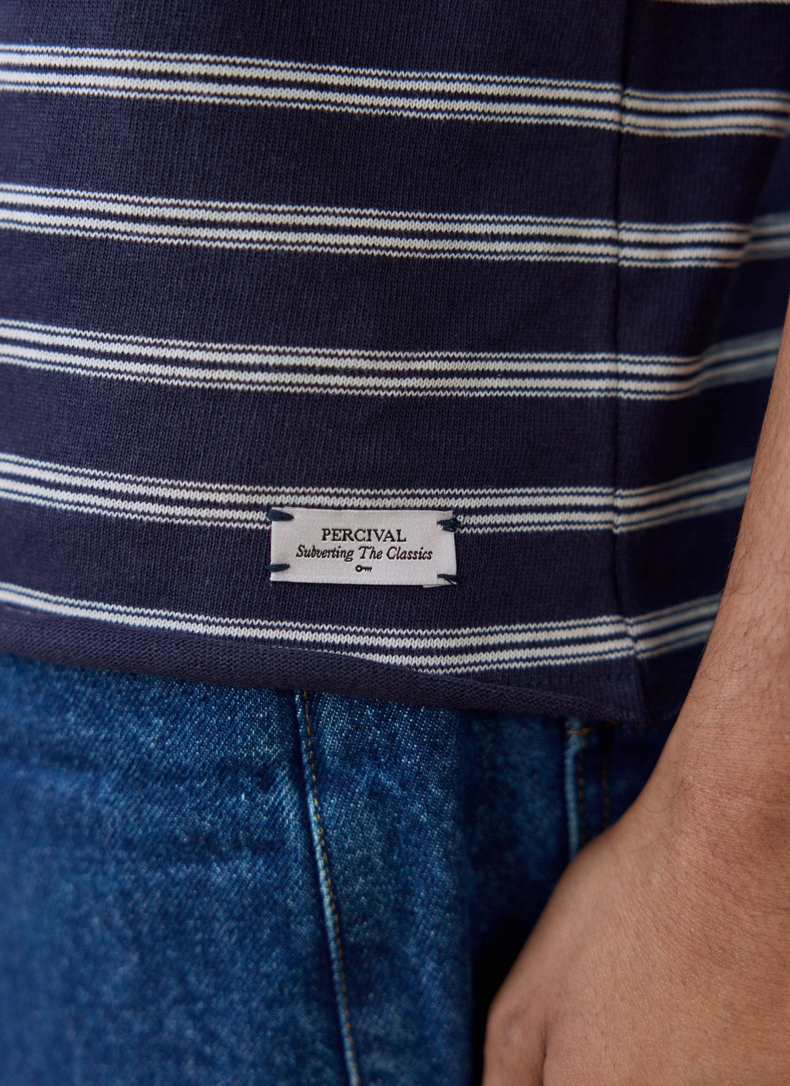 Close-up of the label on the navy striped Percival Arlo Breton T-shirt, reading 'Subverting The Classics'.