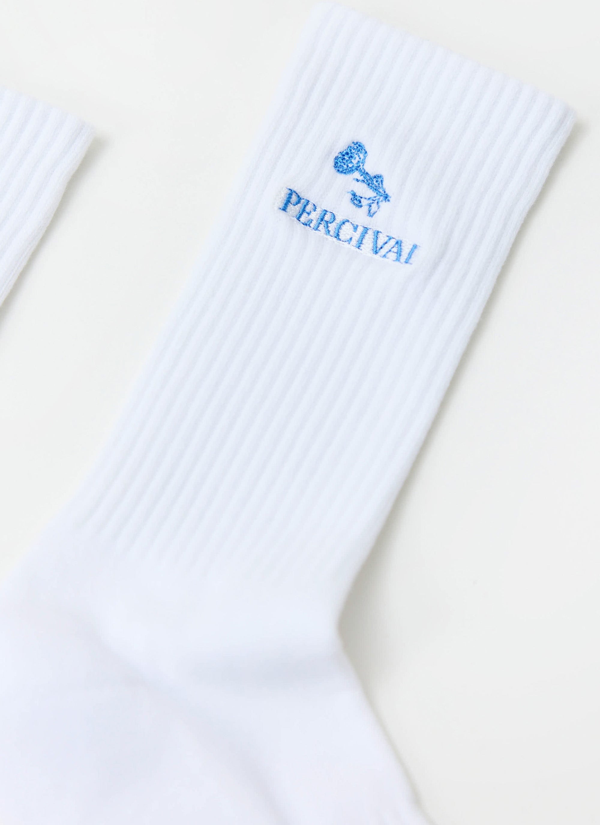 Close-up of the Percival Smith Floral Embroidered Socks in white, showing the blue logo detail on the ribbed cotton.