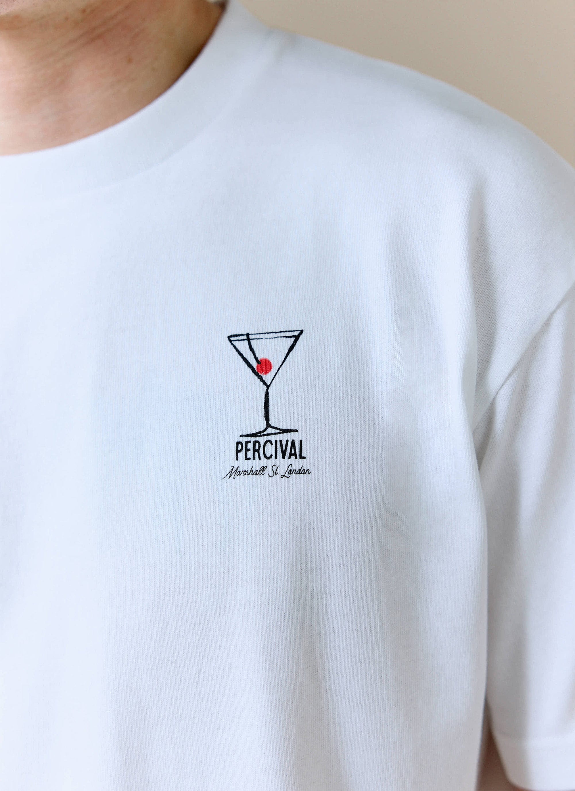 A close-up of the embroidered Perci & Rossi Martini graphic on the white organic cotton t-shirt by Percival.