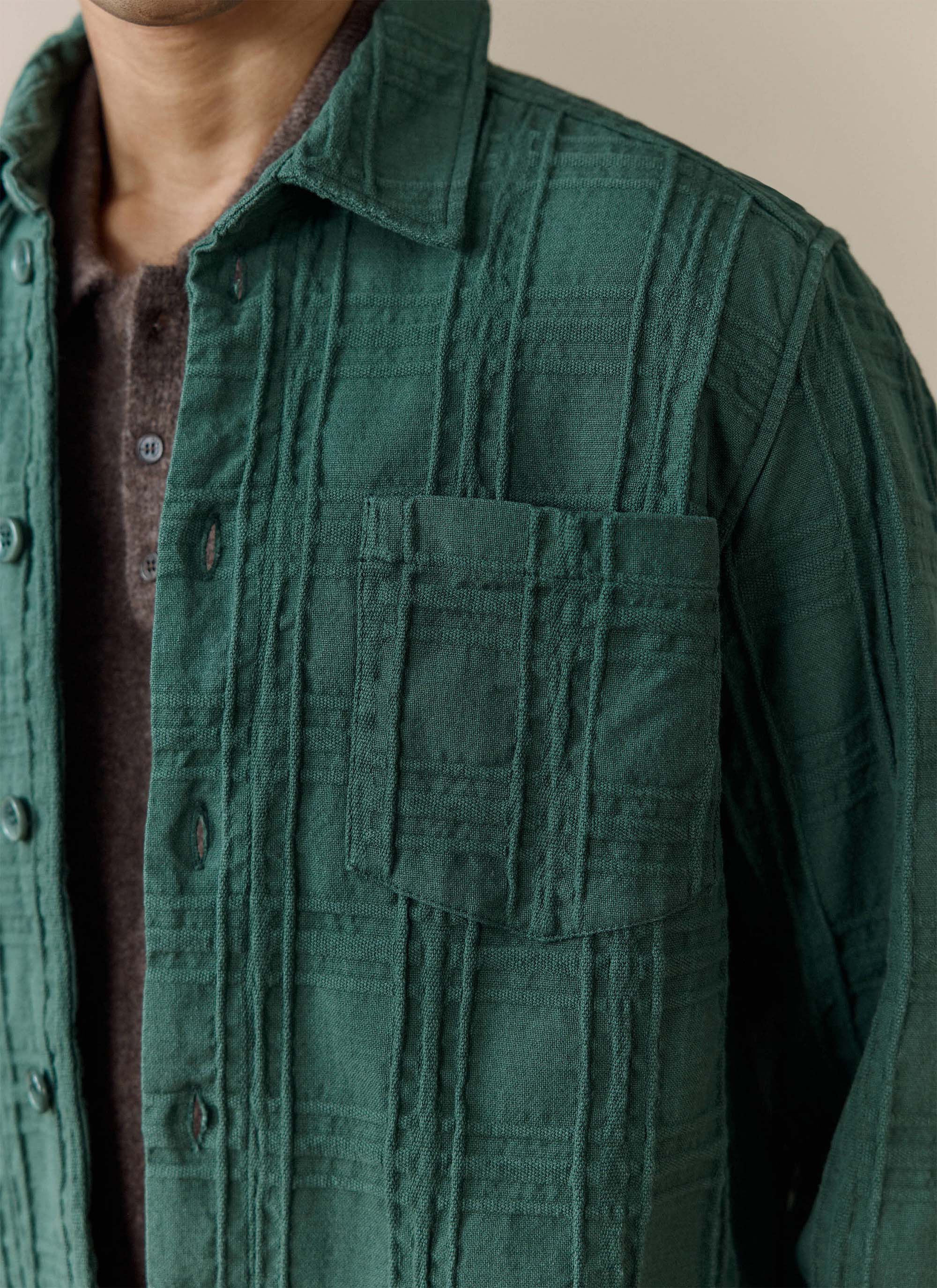A model wears the Percival Canyon Heavyweight Overshirt in Forest, showing the woven cotton texture and chest pocket.