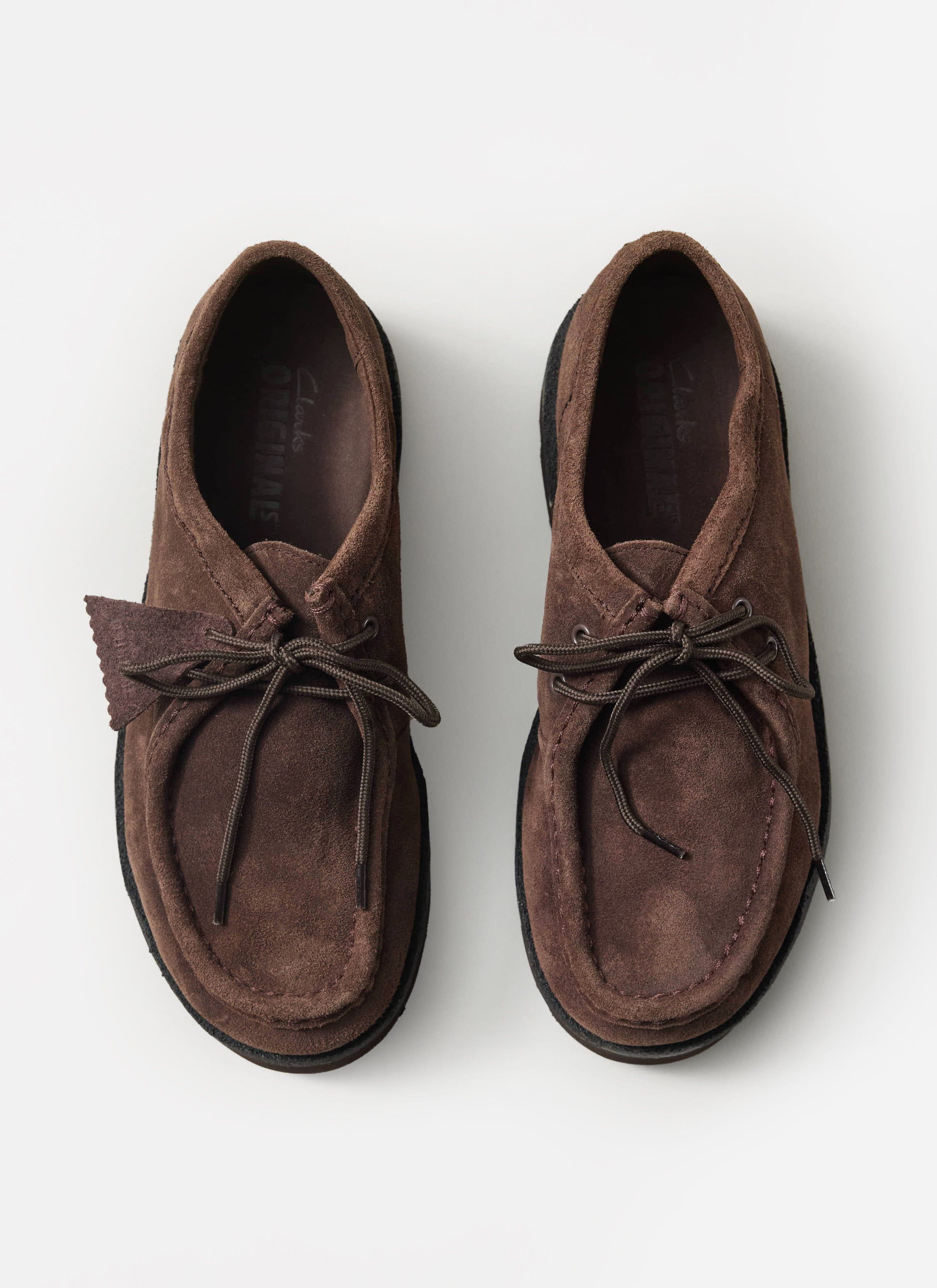 A top-down shot of the Percival x Clarks Originals Meare Walla shoes in dark brown suede, on a white background.
