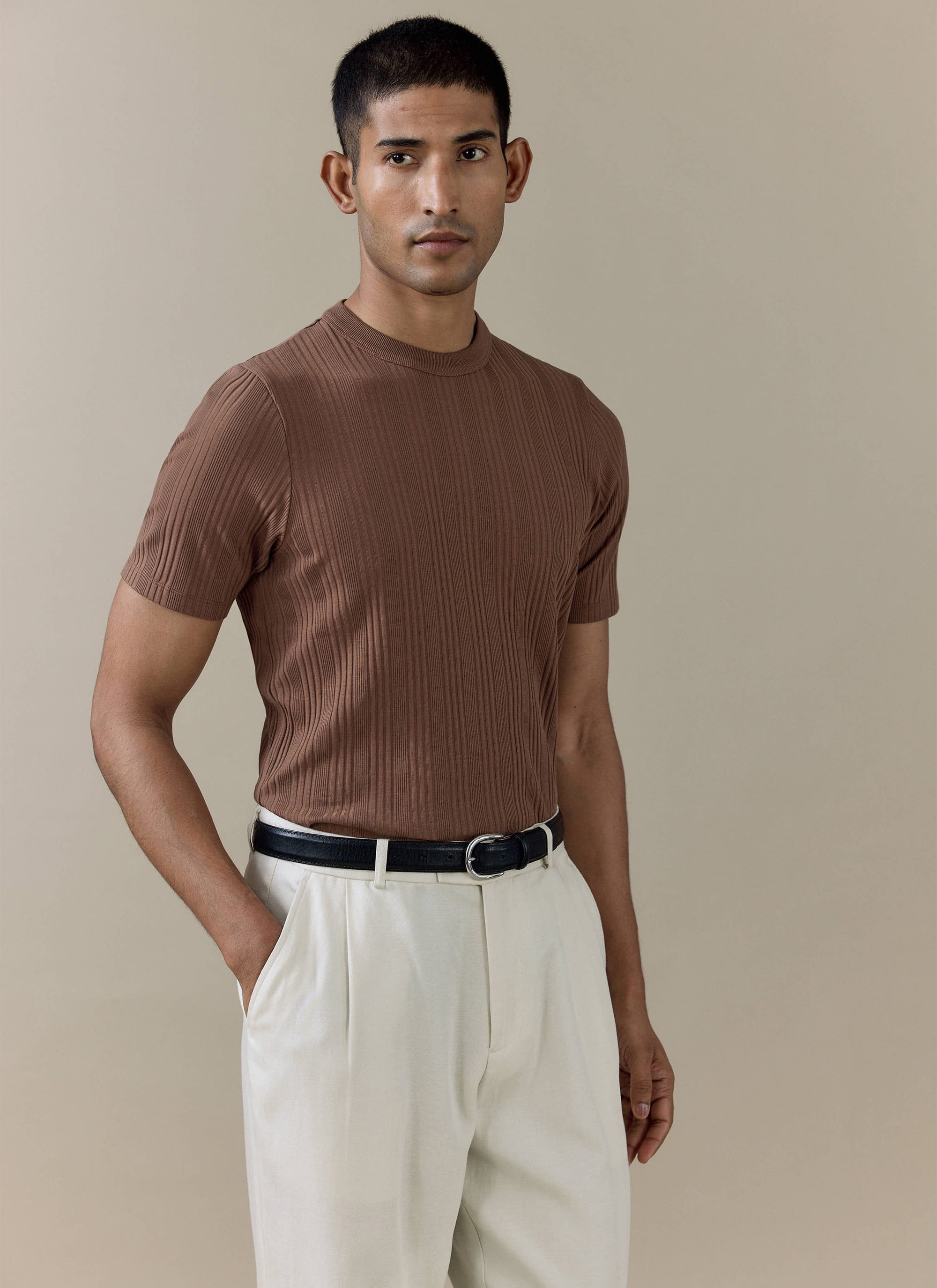 Percival Leon ribbed t-shirt in brown organic cotton, worn by a model with cream trousers.