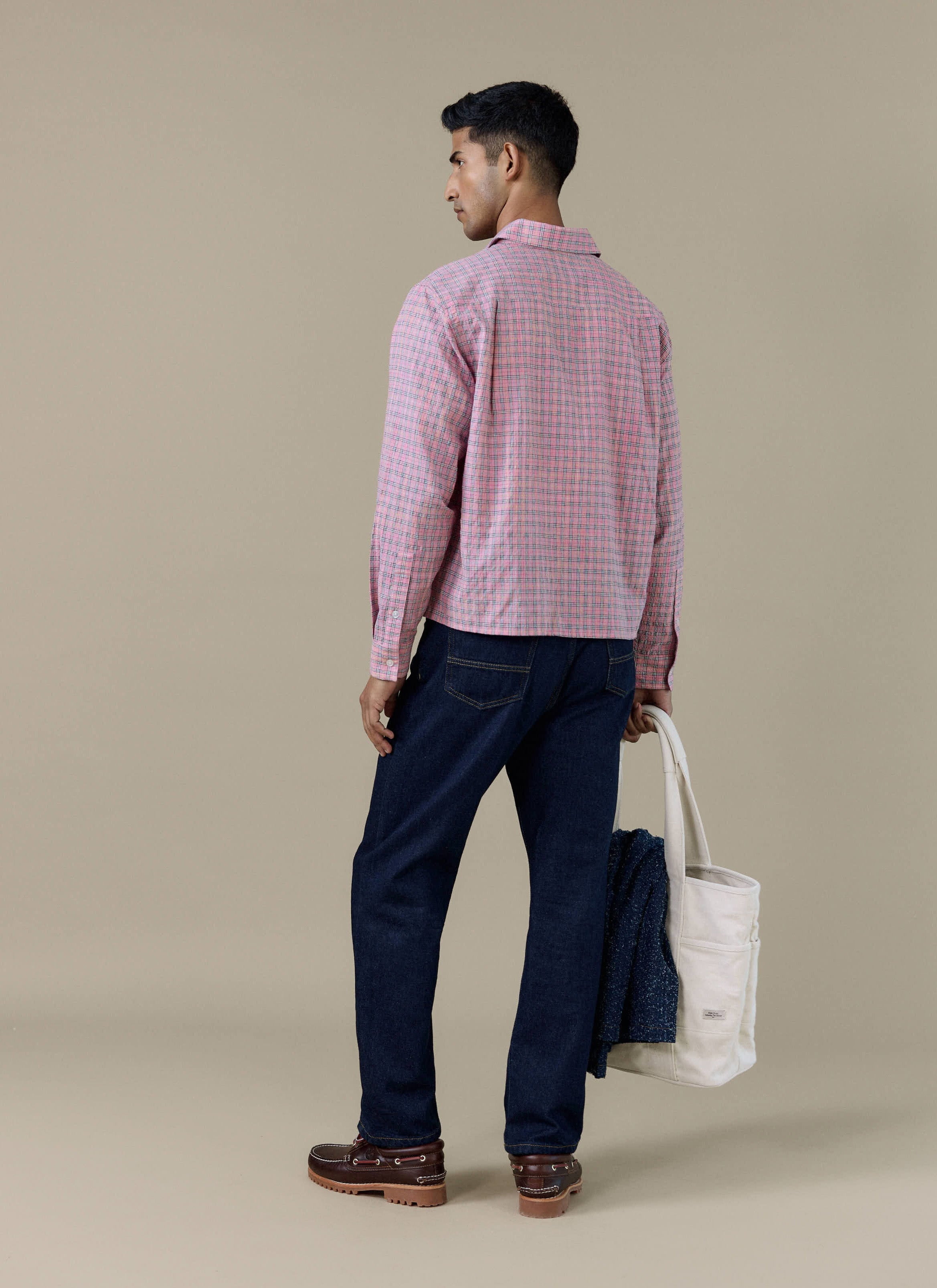 Back view of a model wearing the pink Hinsley Checked Boxy Shirt by Percival, paired with dark denim jeans.