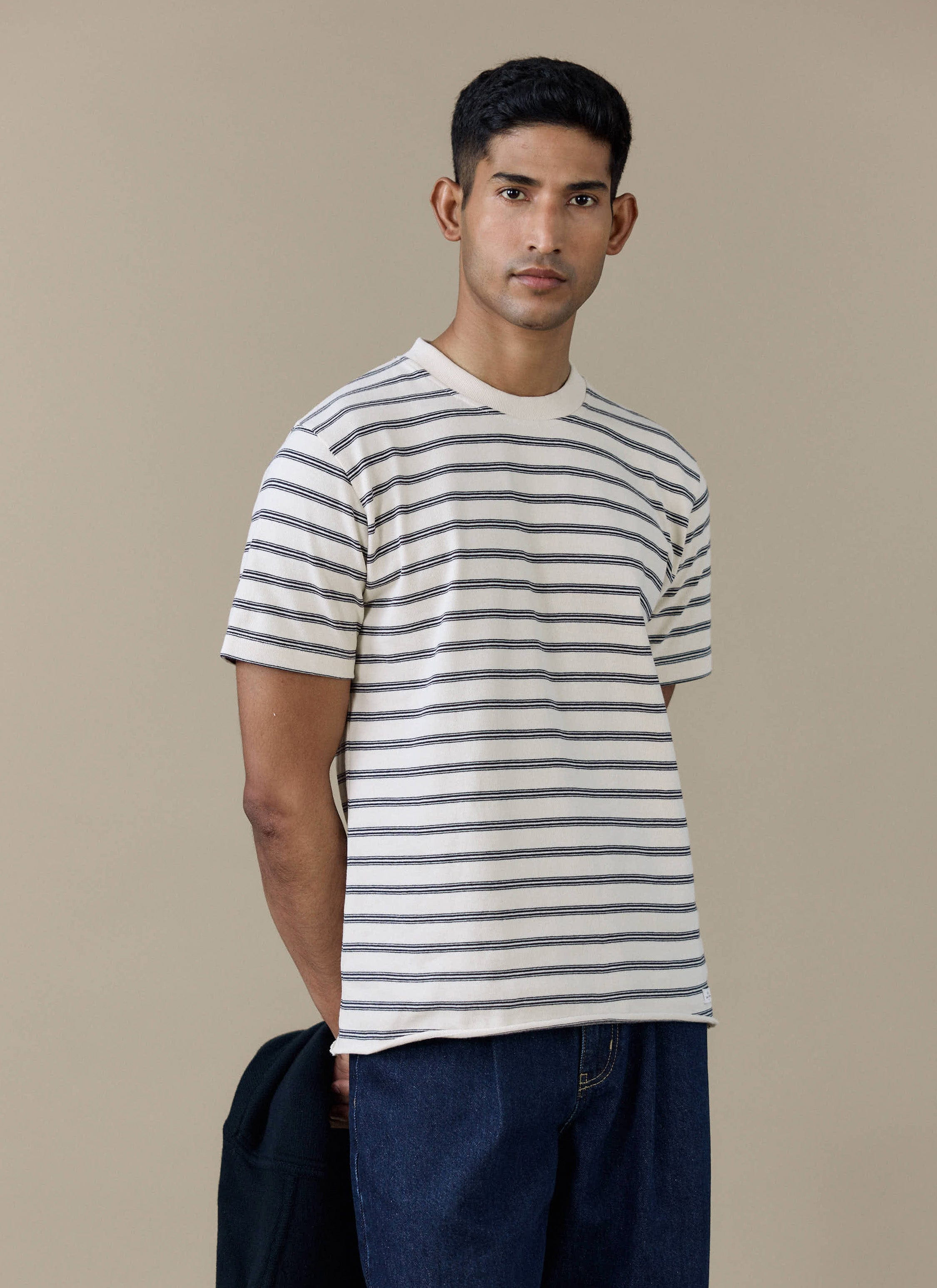 Model wearing the Percival Arlo Raw Hem Breton T-shirt in cream with navy stripes and a raw hem finish.