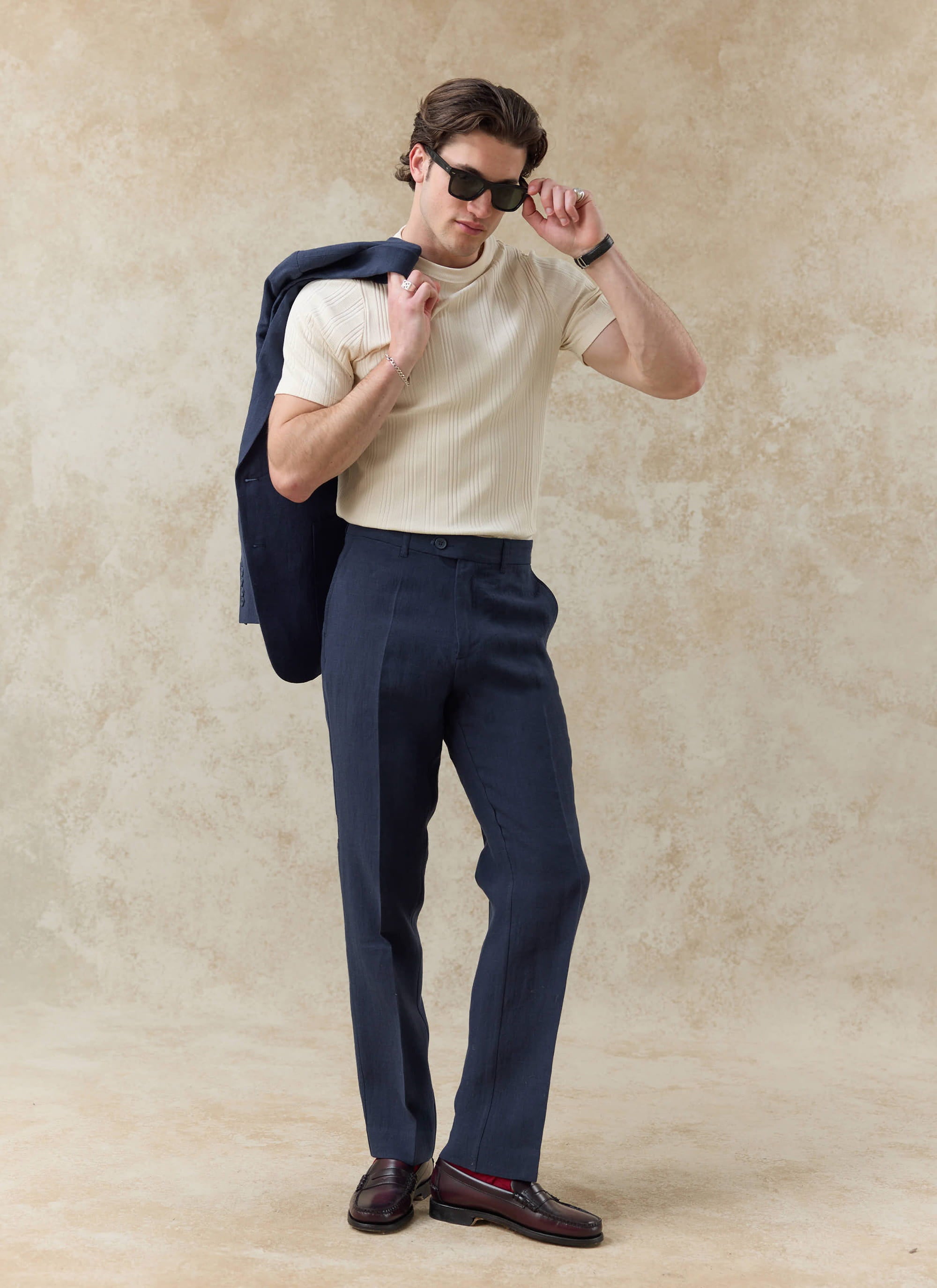 Percival navy tailored linen trousers, styled in a full-body shot with a matching blazer and cream ribbed knit shirt.