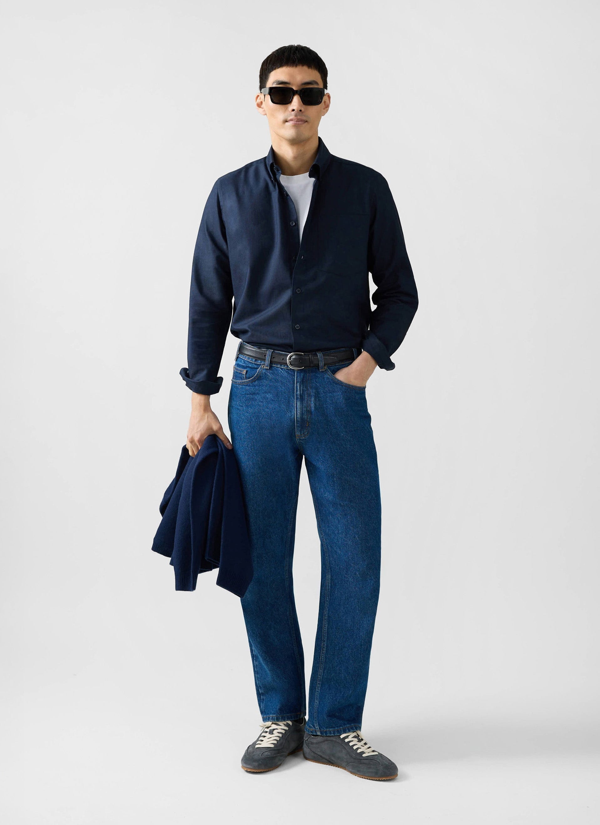 A model styled in the Percival navy Oxford shirt, white t-shirt, blue jeans, and sunglasses.