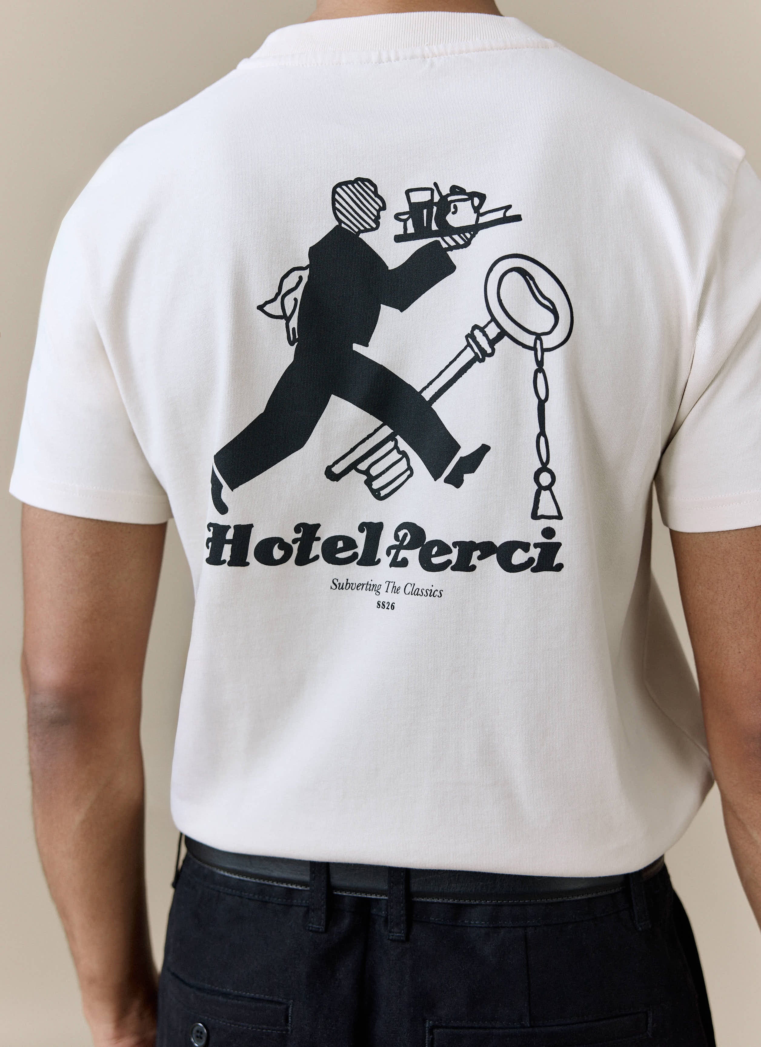 A close-up on the back of a model wearing the ecru Hotel T Shirt from Percival, displaying the 'Hotel Perci' graphic.