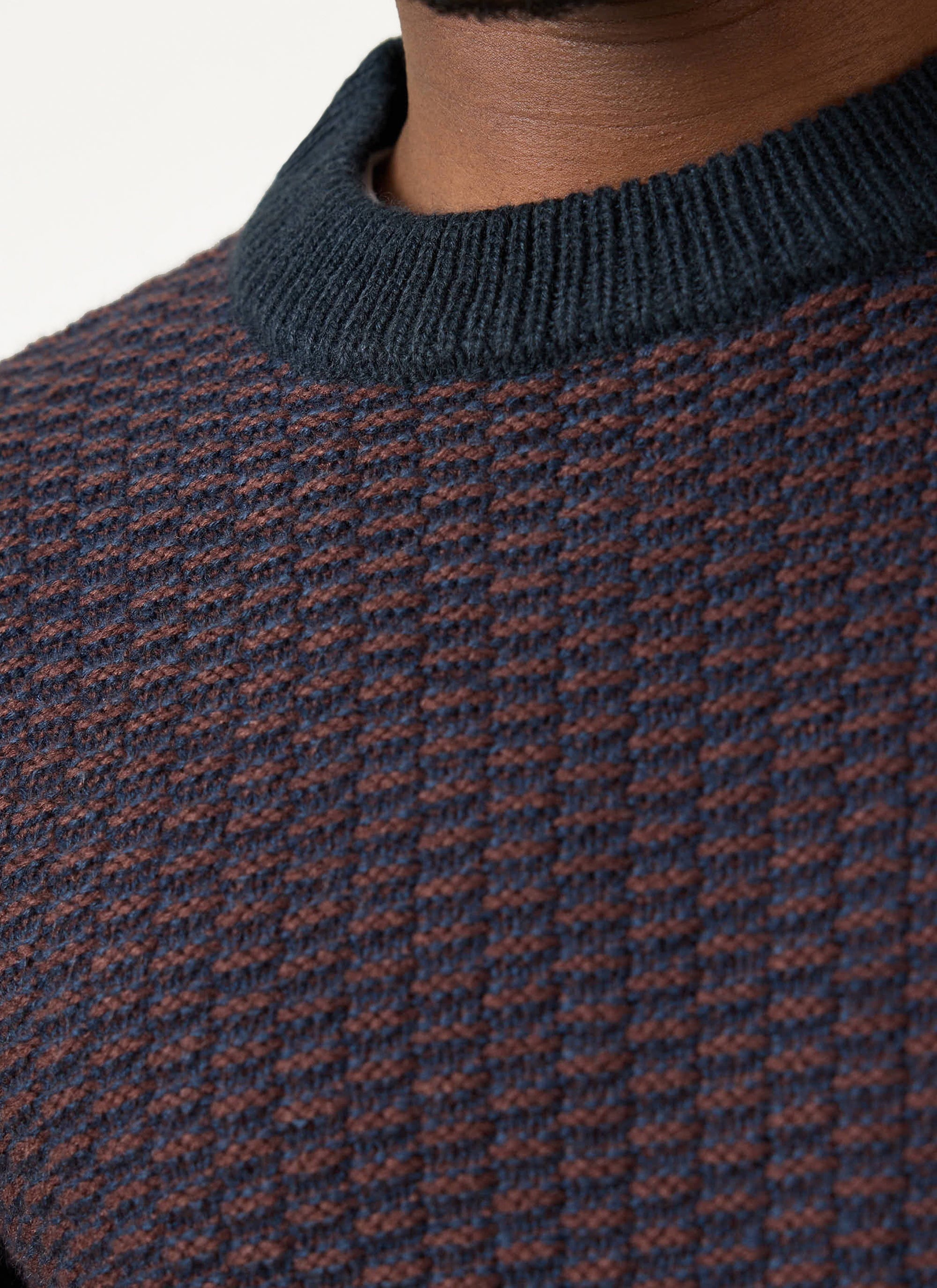 A close-up of a model wearing the Percival Charlestown Jumper, showing the navy and burgundy textured knit and ribbed neck.