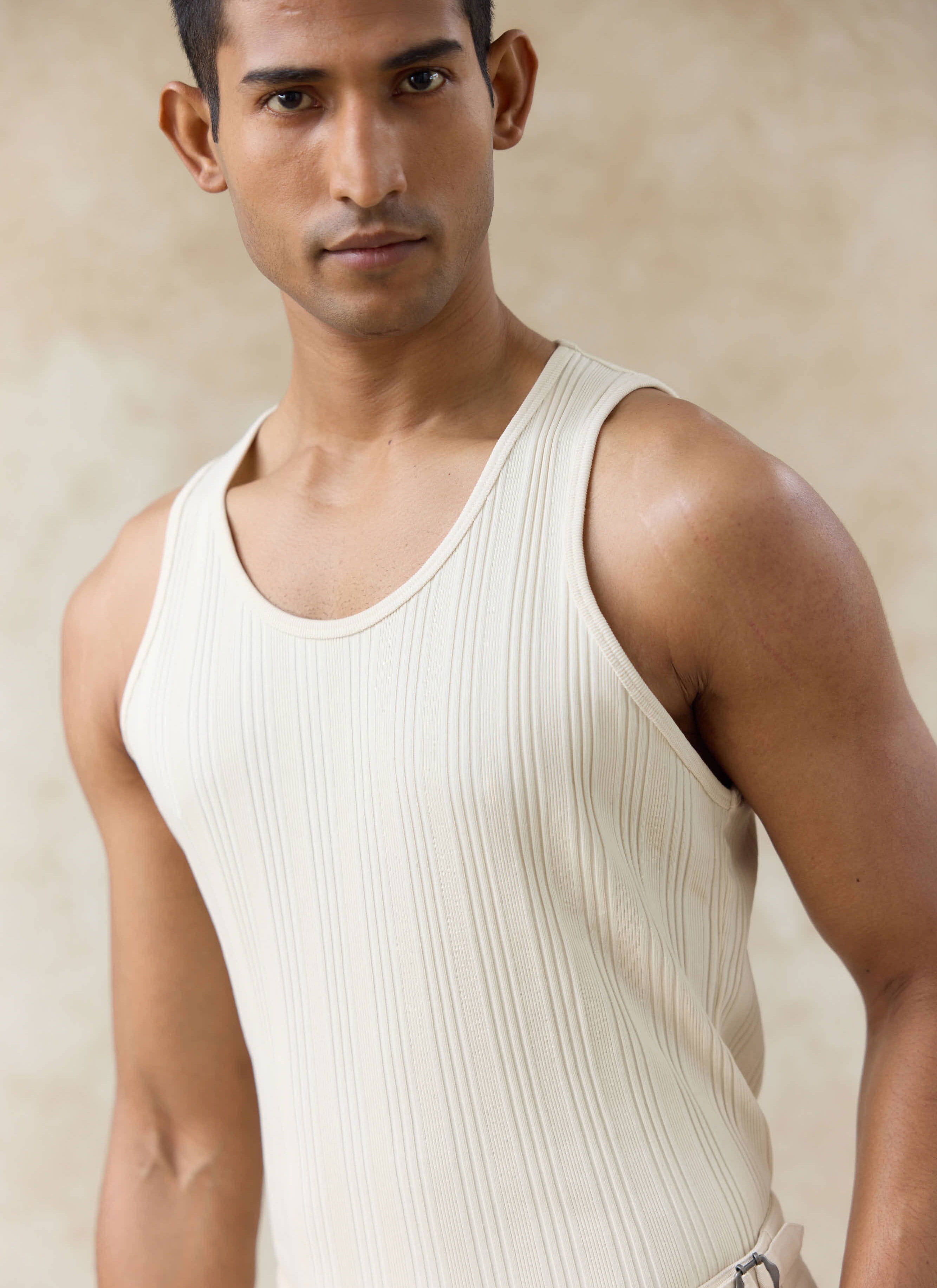 Model wearing the cream-coloured Percival Leon Ribbed Vest, featuring organic cotton jersey and a classic scoop neck.