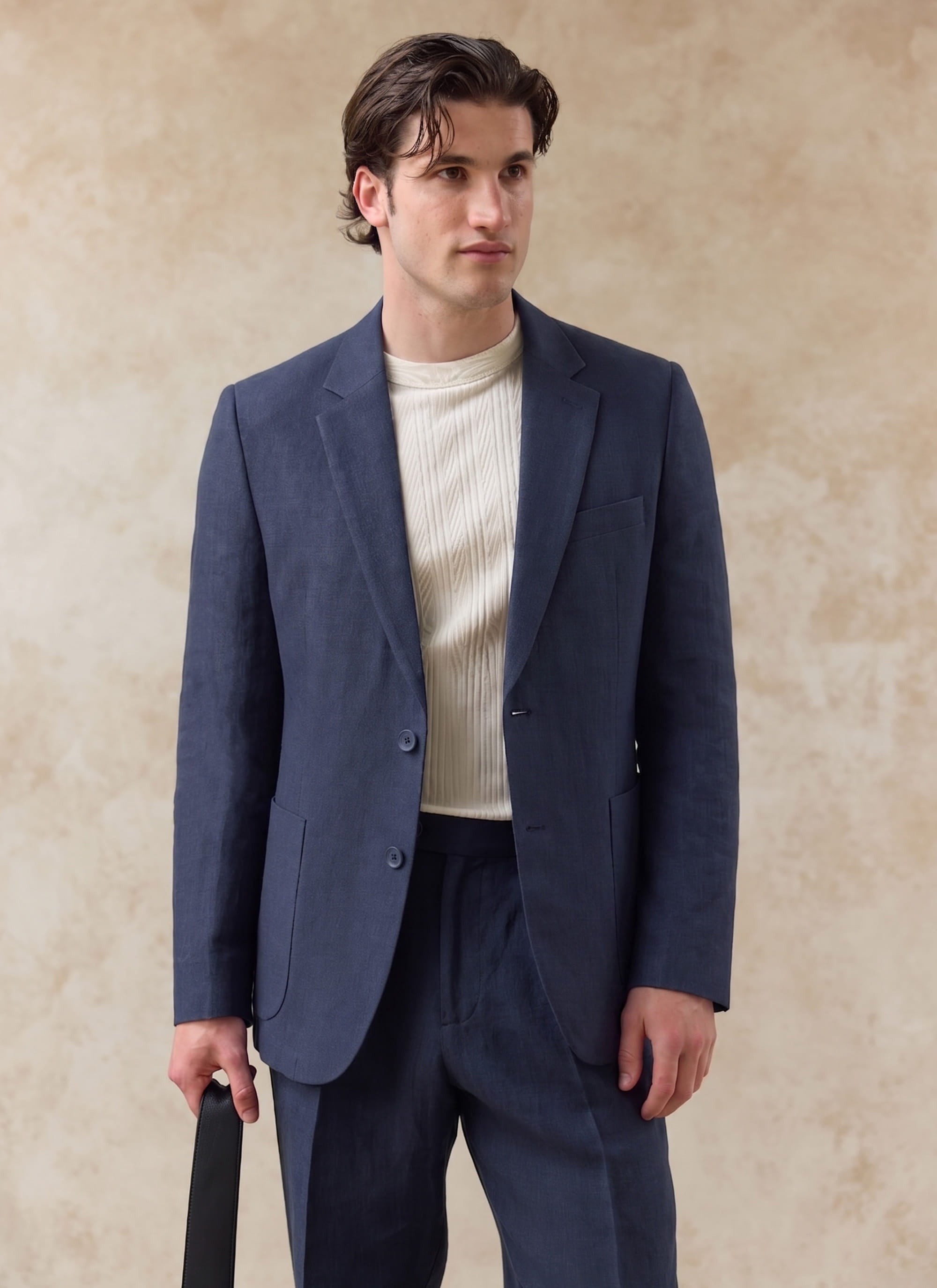 Navy blue tailored linen blazer by Percival, worn by a model with a cream textured shirt and matching trousers.