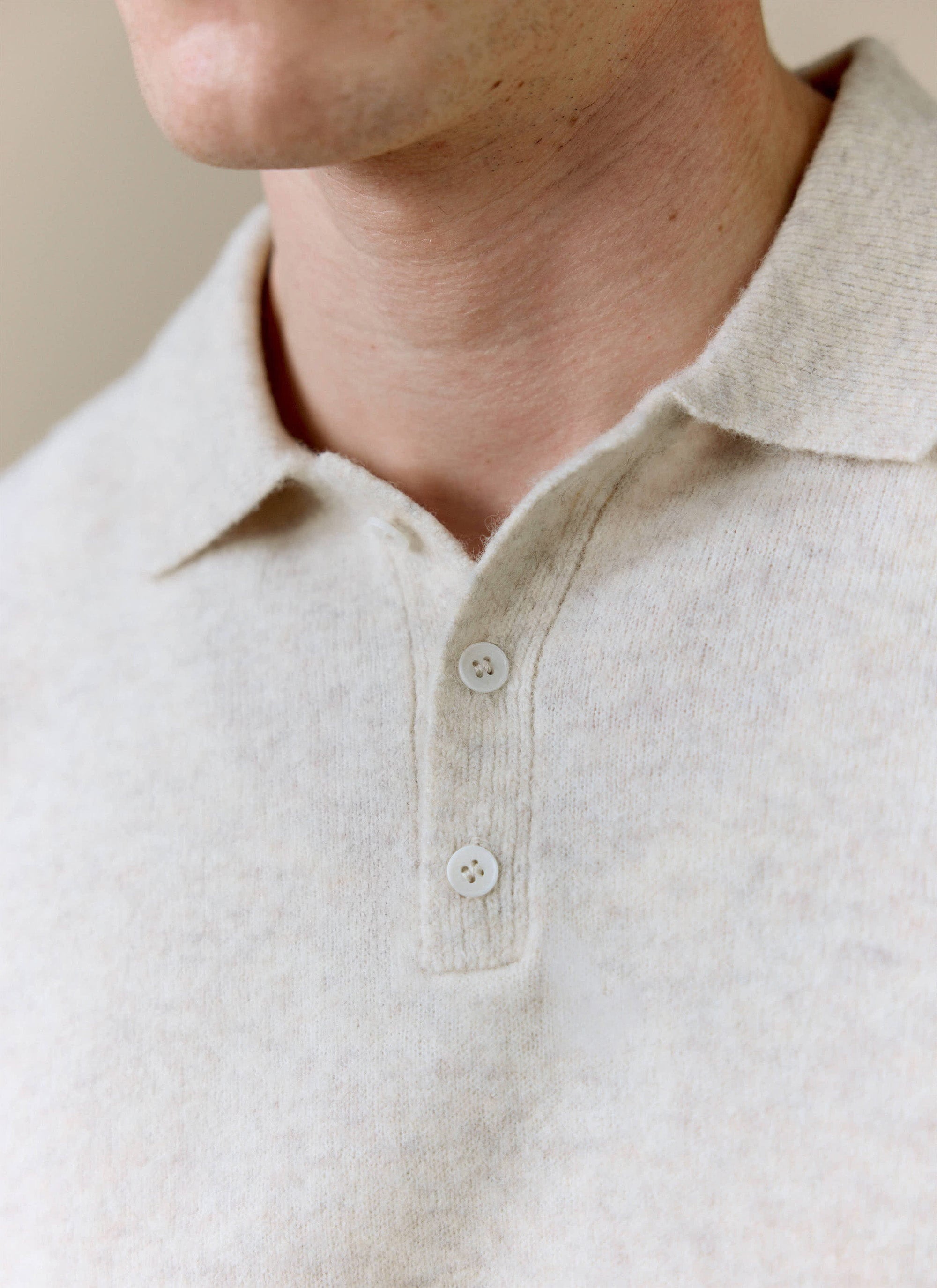 A close-up of the Percival Collins Boxy Knitted Polo in ecru, showing the soft yak-wool blend texture and two-button placket.