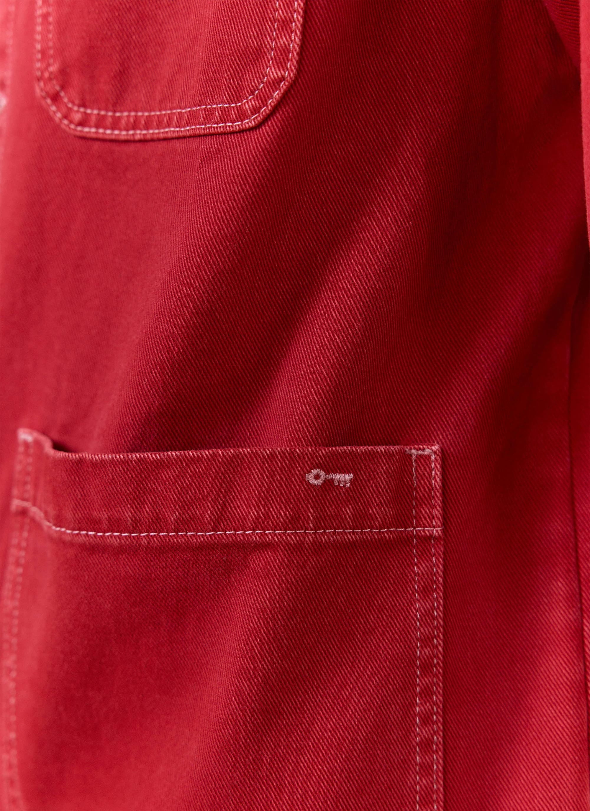 Detail of the red cotton canvas pocket with white key embroidery on the Percival Oliver Chore Jacket.