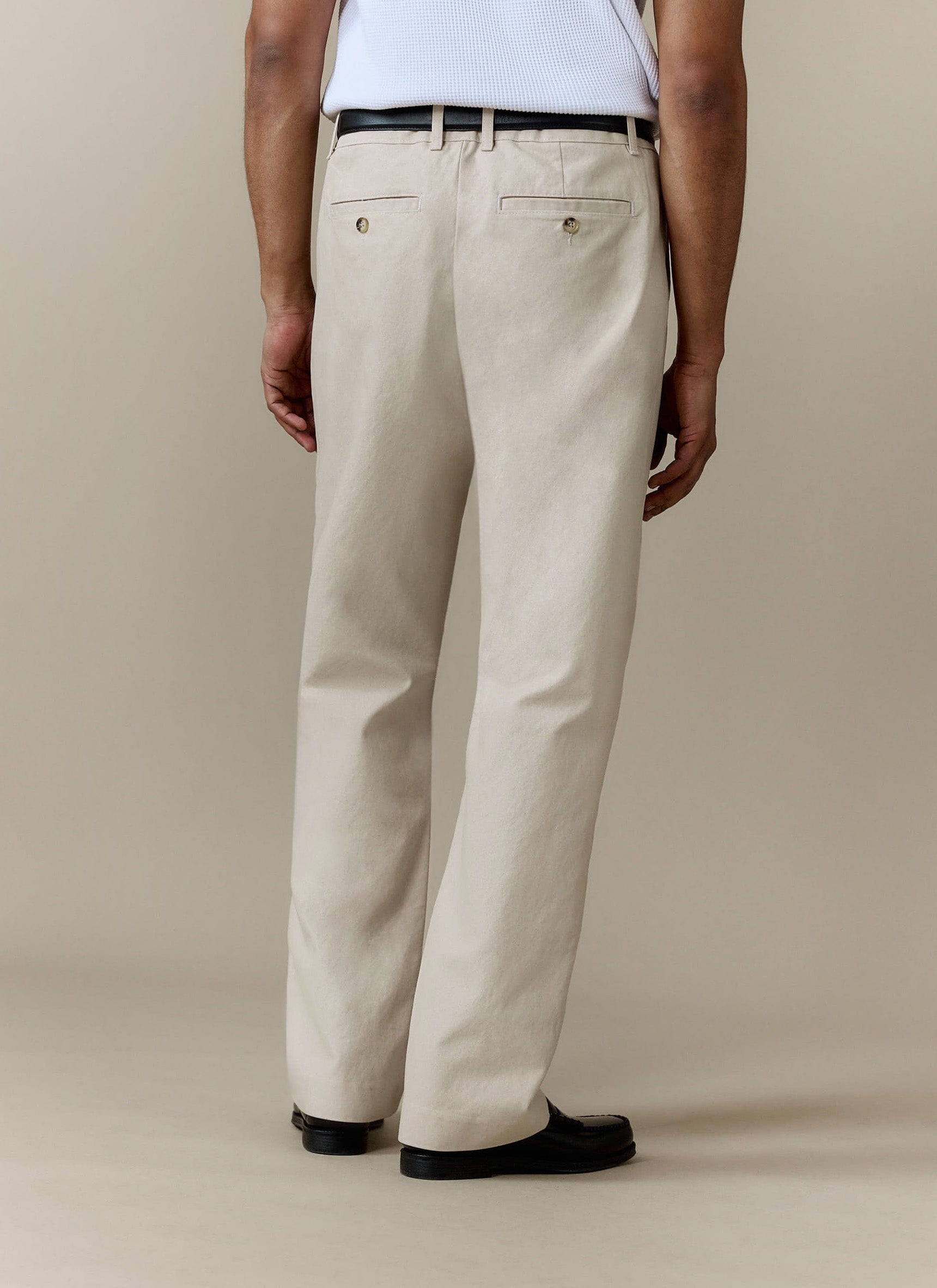 Rear view of a model wearing the Percival Seb Inverted Pleat Trousers in ecru, showing the relaxed fit and back pockets.