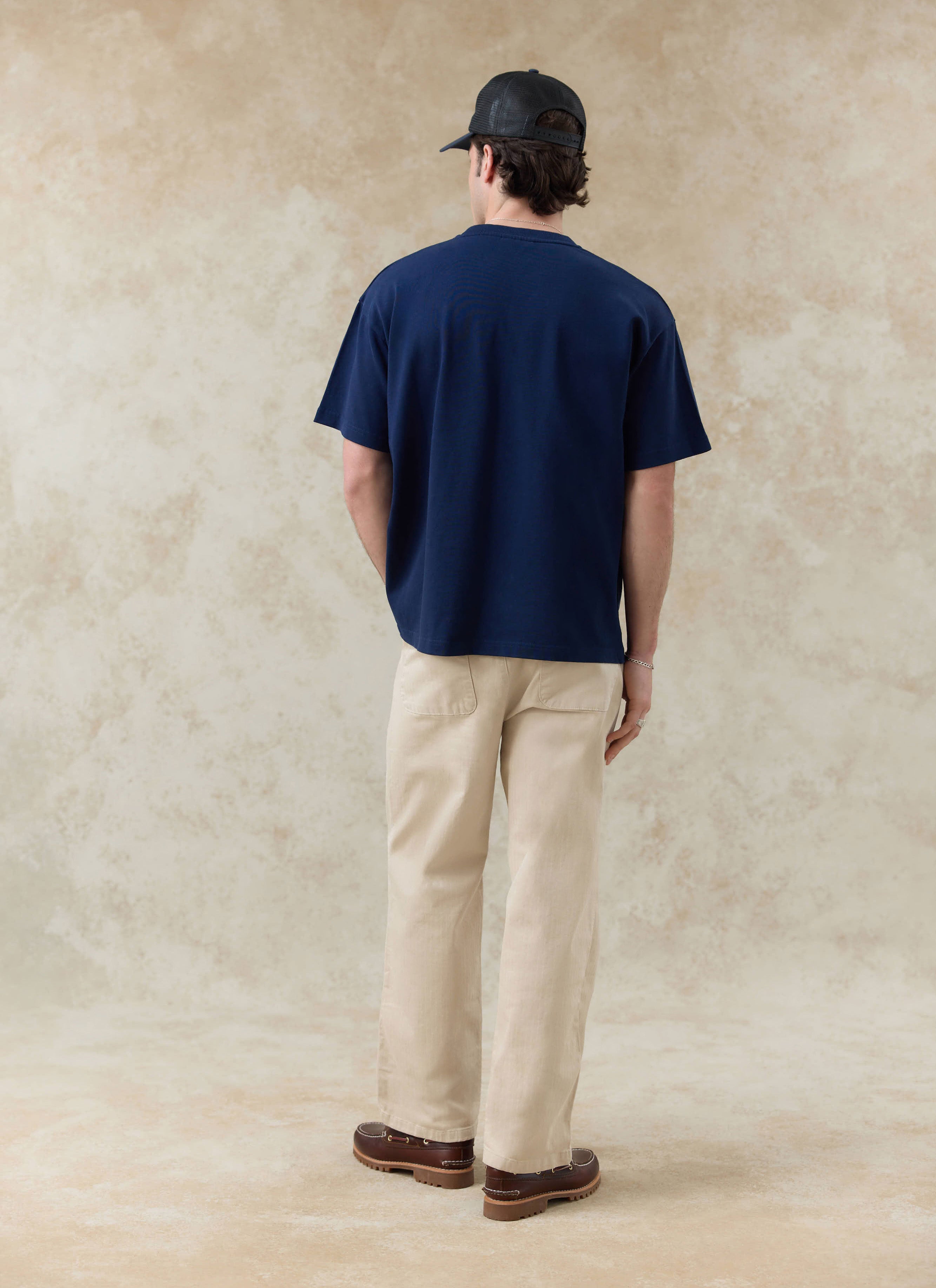 Navy Percival Clarke embroidered organic cotton t-shirt, seen from the back with beige trousers from the SS26 range.