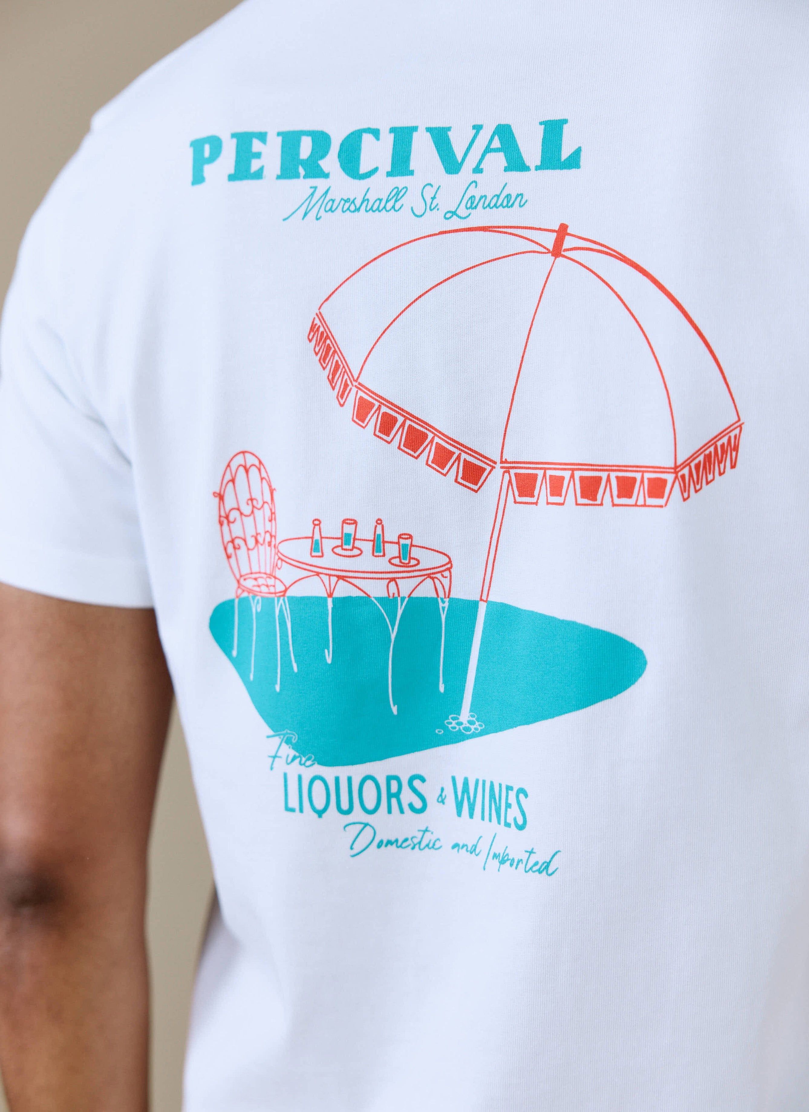 Close-up of the back of the white Percival Perci Fine Wines T-shirt, showing the red and teal café-inspired graphic.