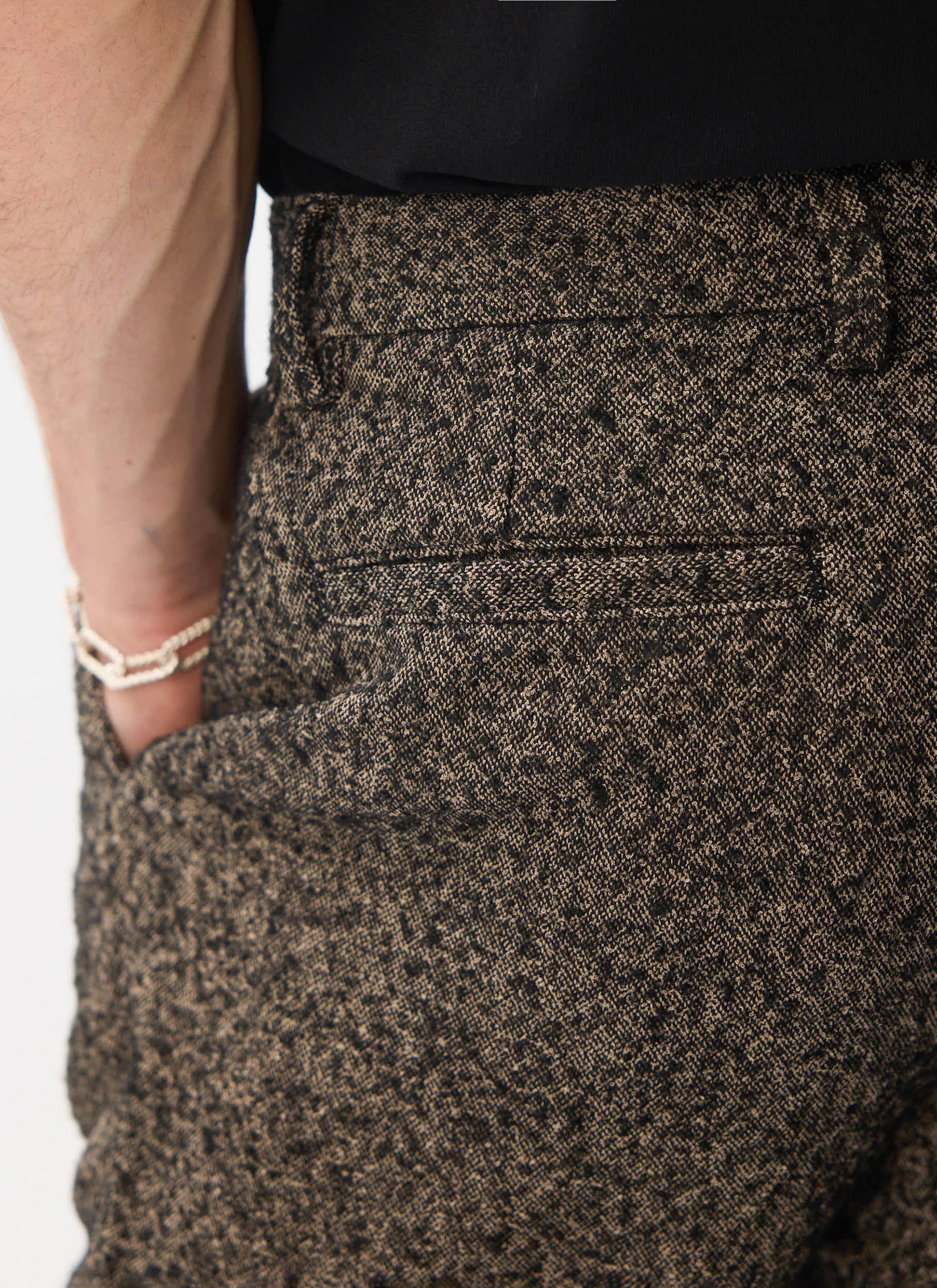 A close-up shot of the back of the Percival Blyton Trousers in grey, highlighting the warm nep blend fabric and jet pocket.