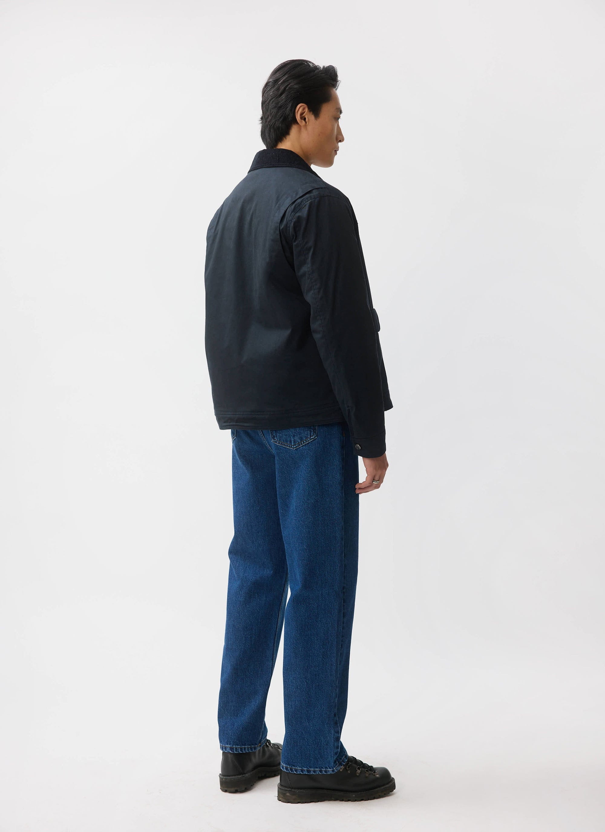 A model shows the back of the navy Fontane Wax Jacket from Percival, highlighting the action back and corduroy collar.
