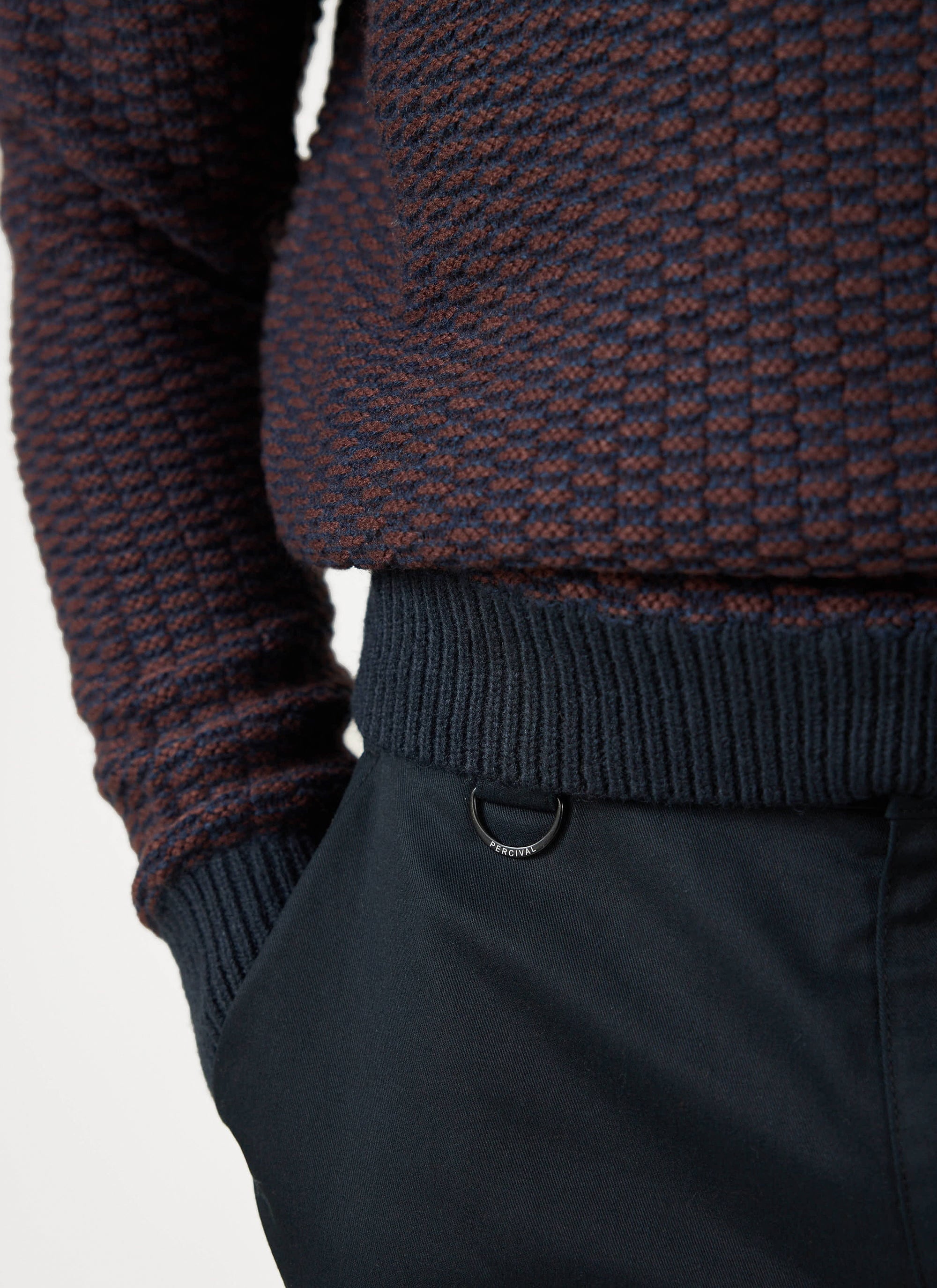 Close-up of the Percival Charlestown Knitted Jumper in navy and burgundy, showing the textured knit and branded D-ring.