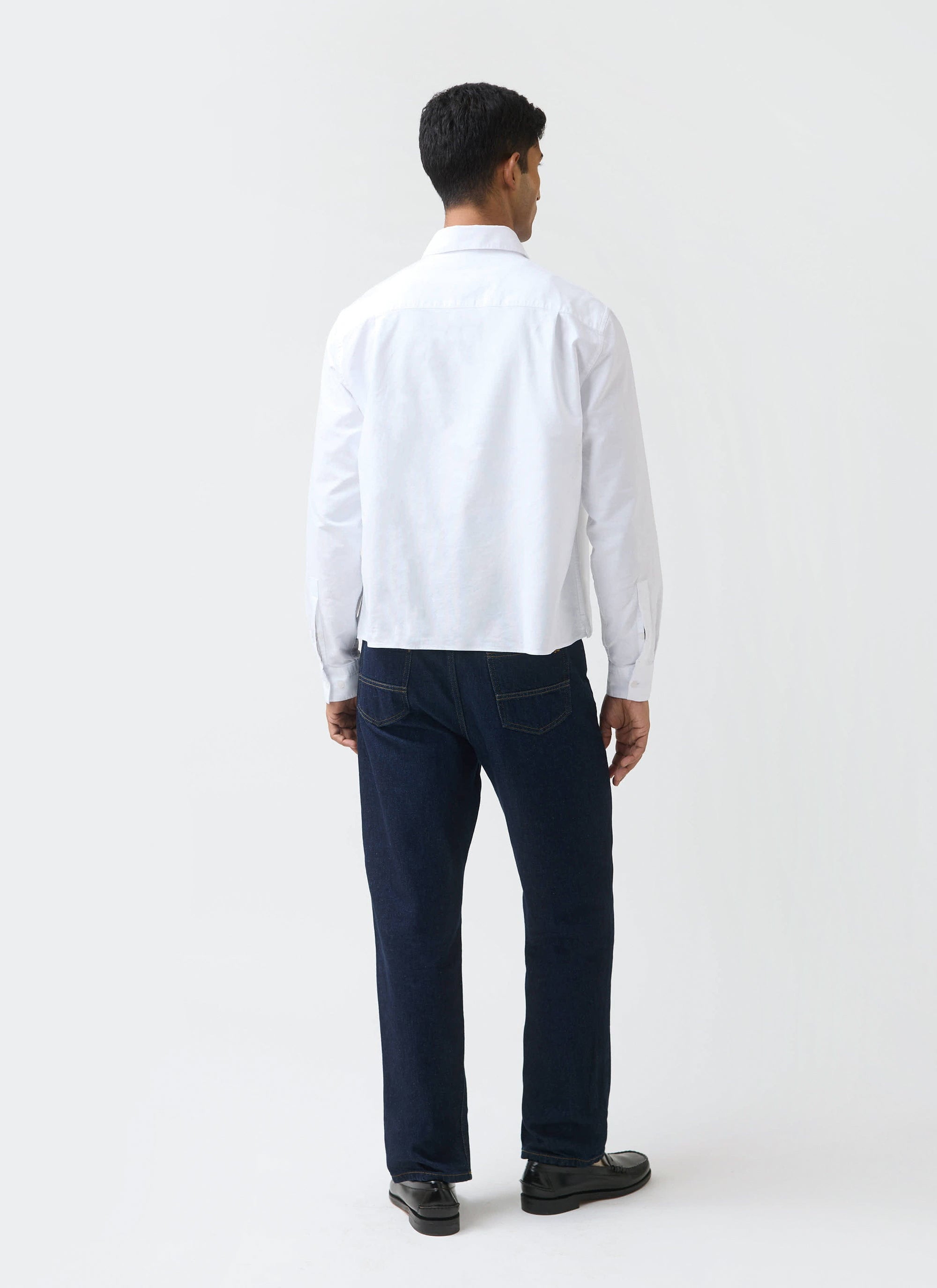 A full-length, back view of a model wearing the white Button Down Boxy Shirt from the Guinness x Percival collection.