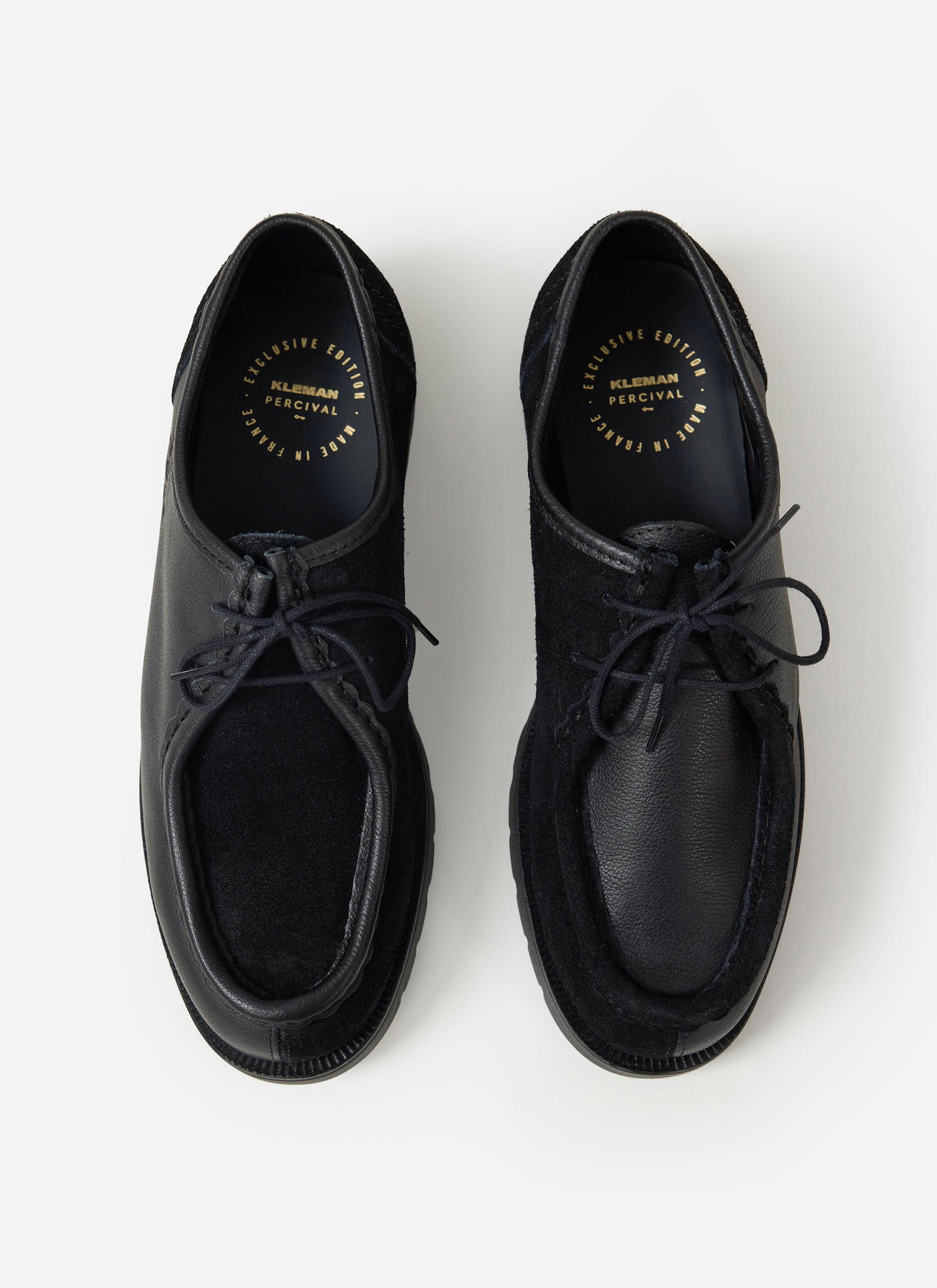 A top-down view of the black leather and suede Kleman x Percival Padror shoes, showing the patchwork 'yin-yang' design.