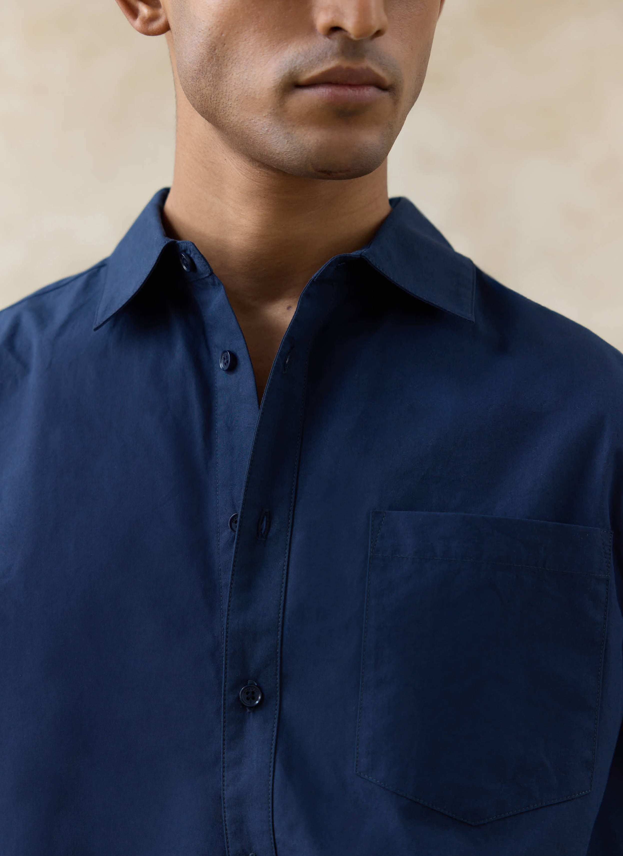 Close-up of the navy Percival Dali Relaxed Poplin Shirt, showing the crisp cotton fabric, collar, and chest pocket.