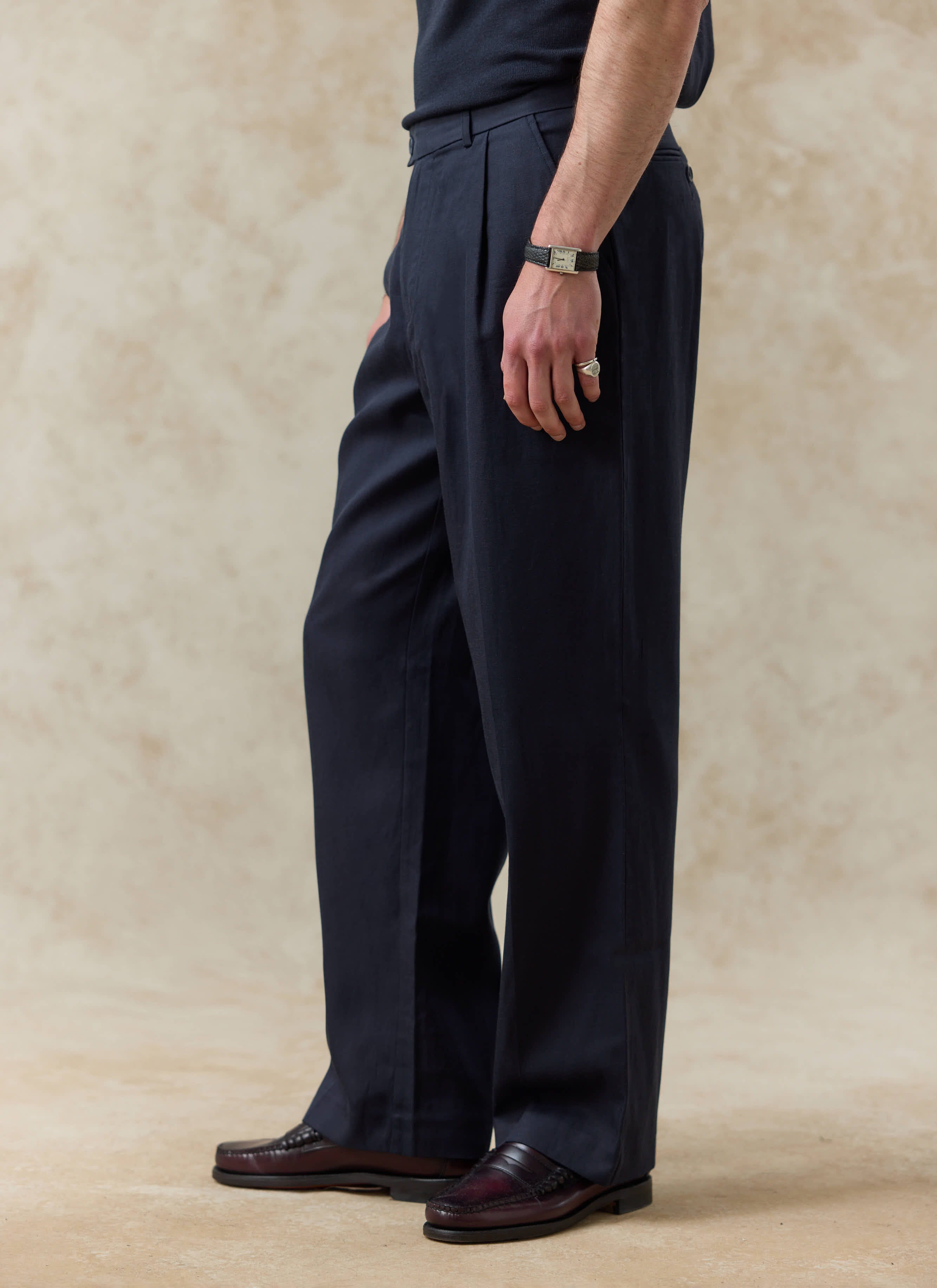 Percival navy blue pleated trousers in soft lyocell, showing the relaxed fit and elegant drape from a side profile.