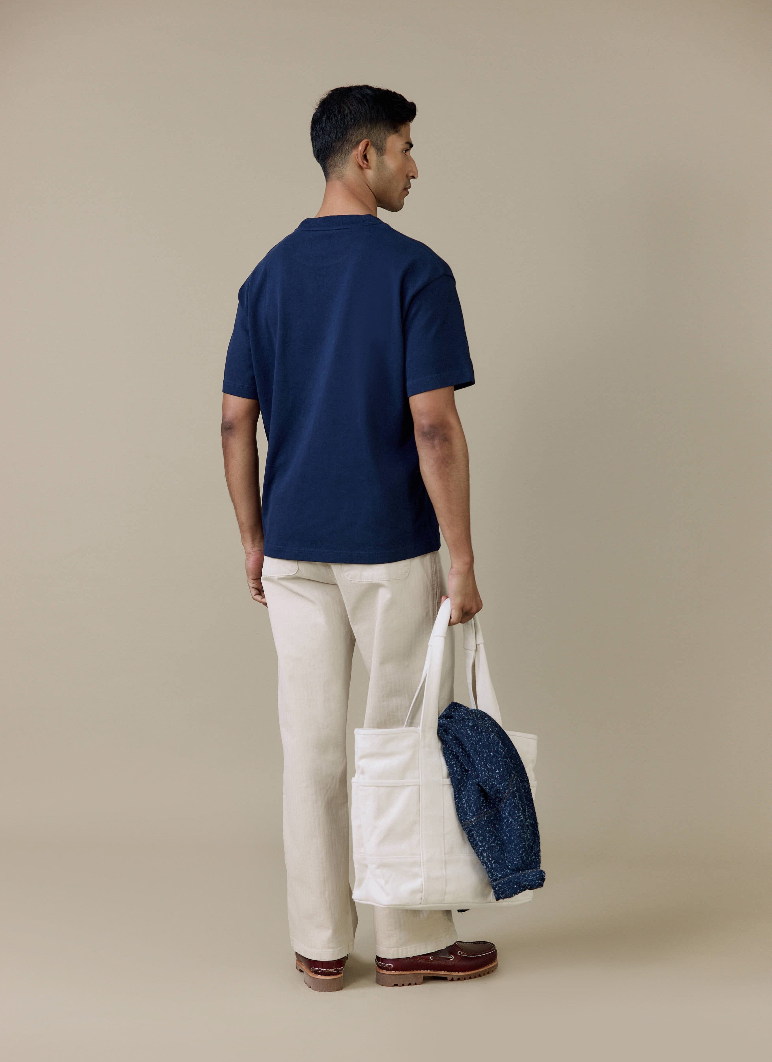 Rear view of a model wearing the navy organic cotton Perci Script T Shirt by Percival, showing the relaxed, boxy fit.