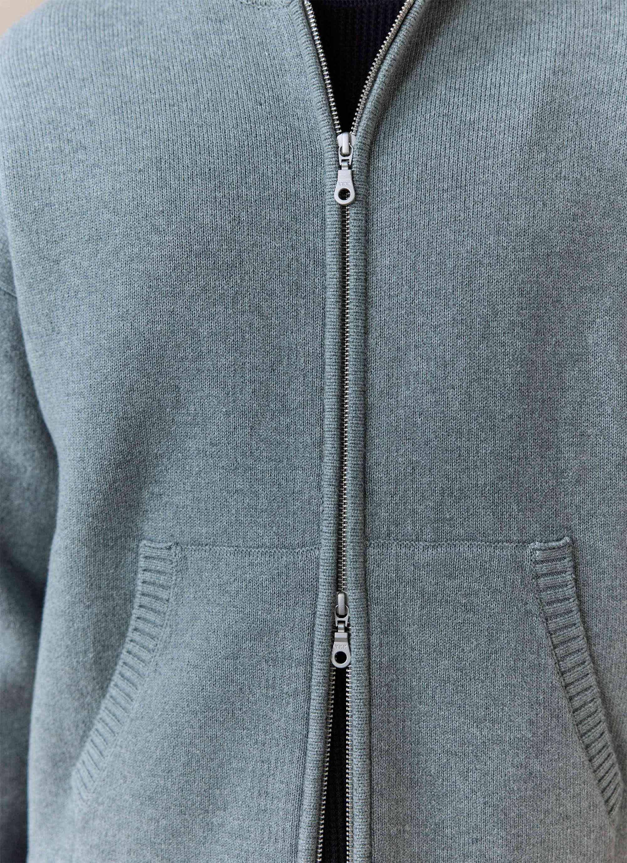 A close-up of the Percival Chronicle Knitted Hoodie in grey, showing the cotton knit texture and central silver zip.