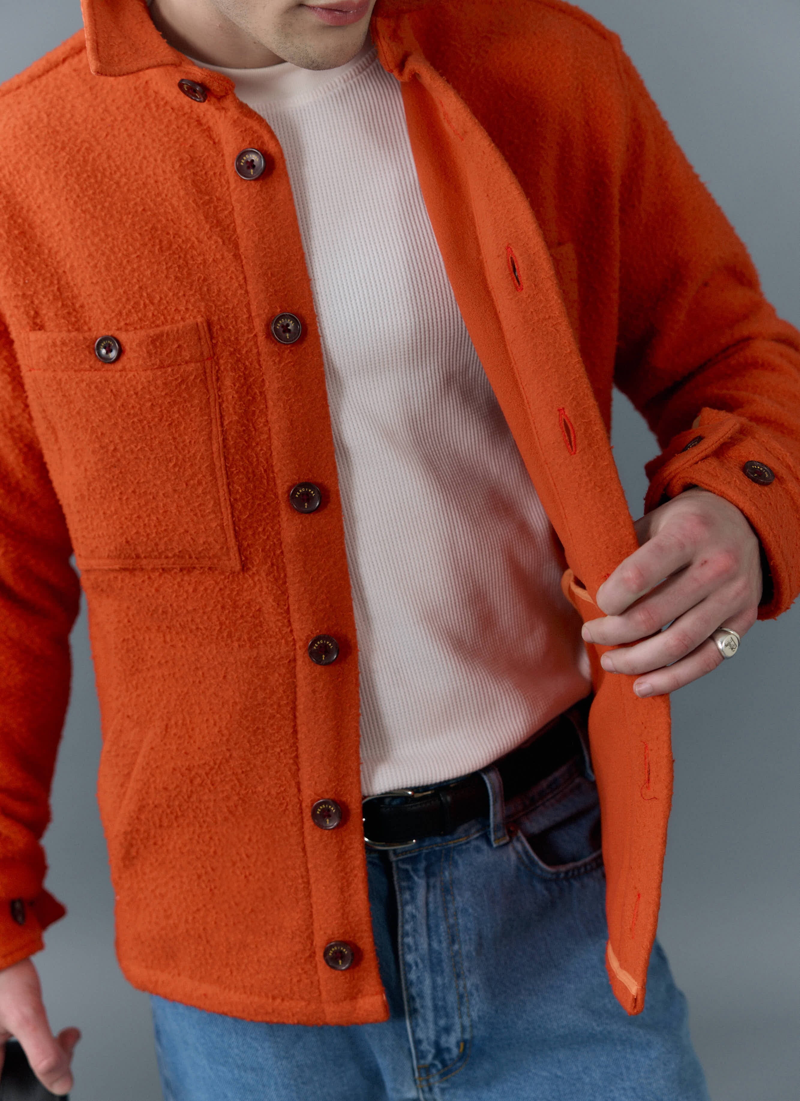 Close-up of a model wearing the Percival orange Blanket Overshirt in Casentino wool over a white t-shirt and jeans.