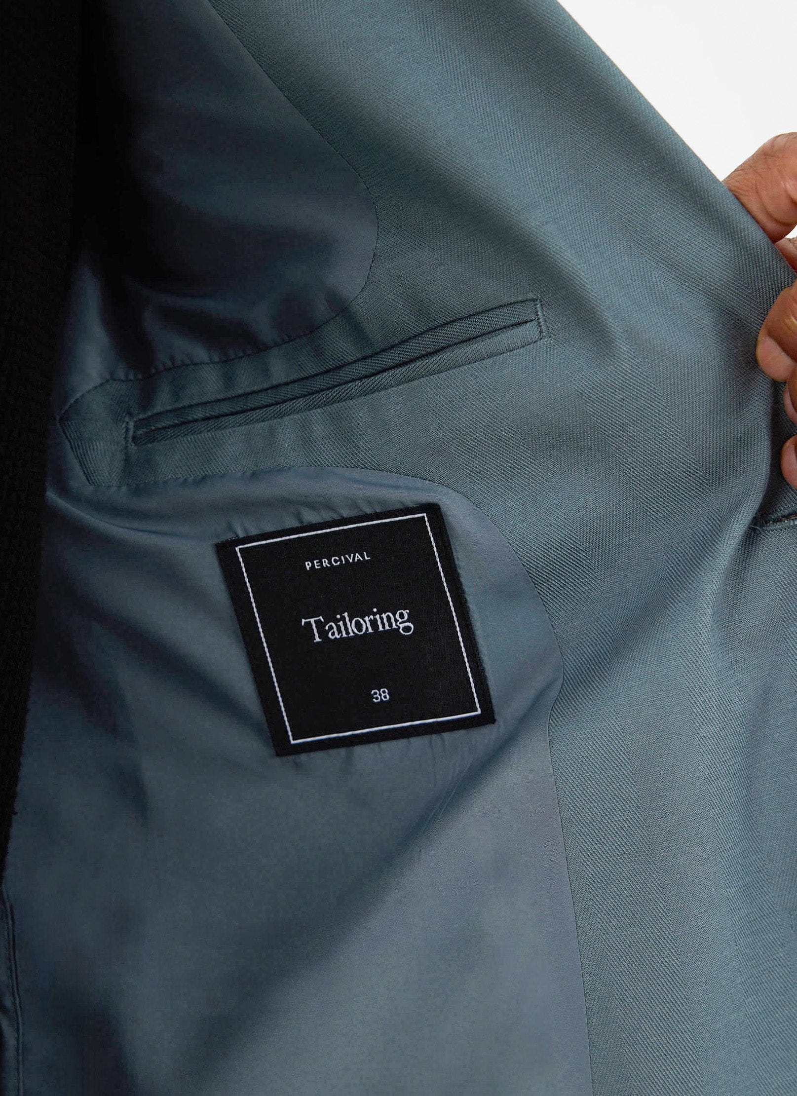 Close-up of the internal 'Percival Tailoring' label and pocket detail of the Lyocell Regular Blazer in Slate Blue.