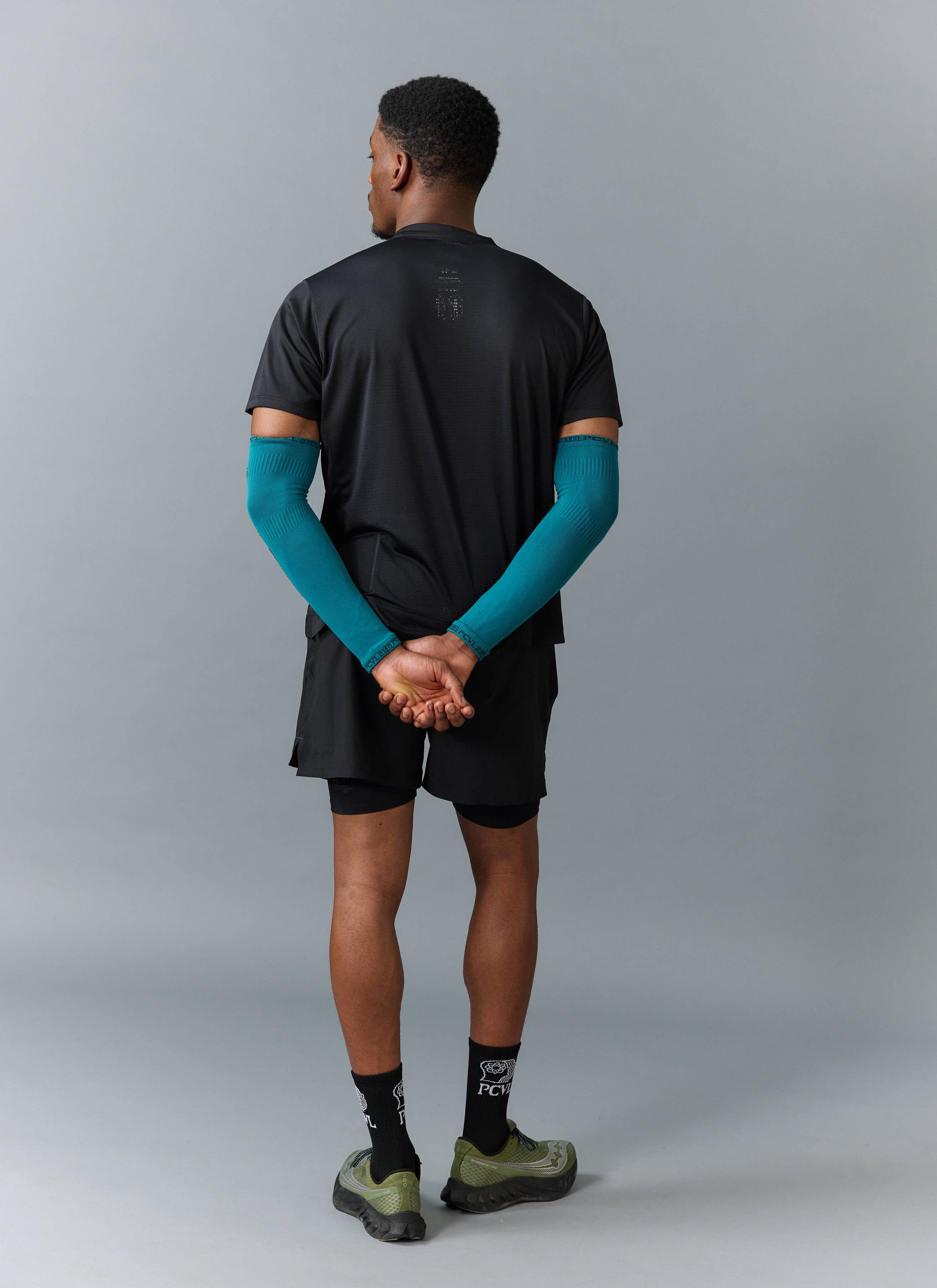 Rear view of a model wearing the Percival black performance t-shirt, showing the fit and subtle graphic detail on the back.