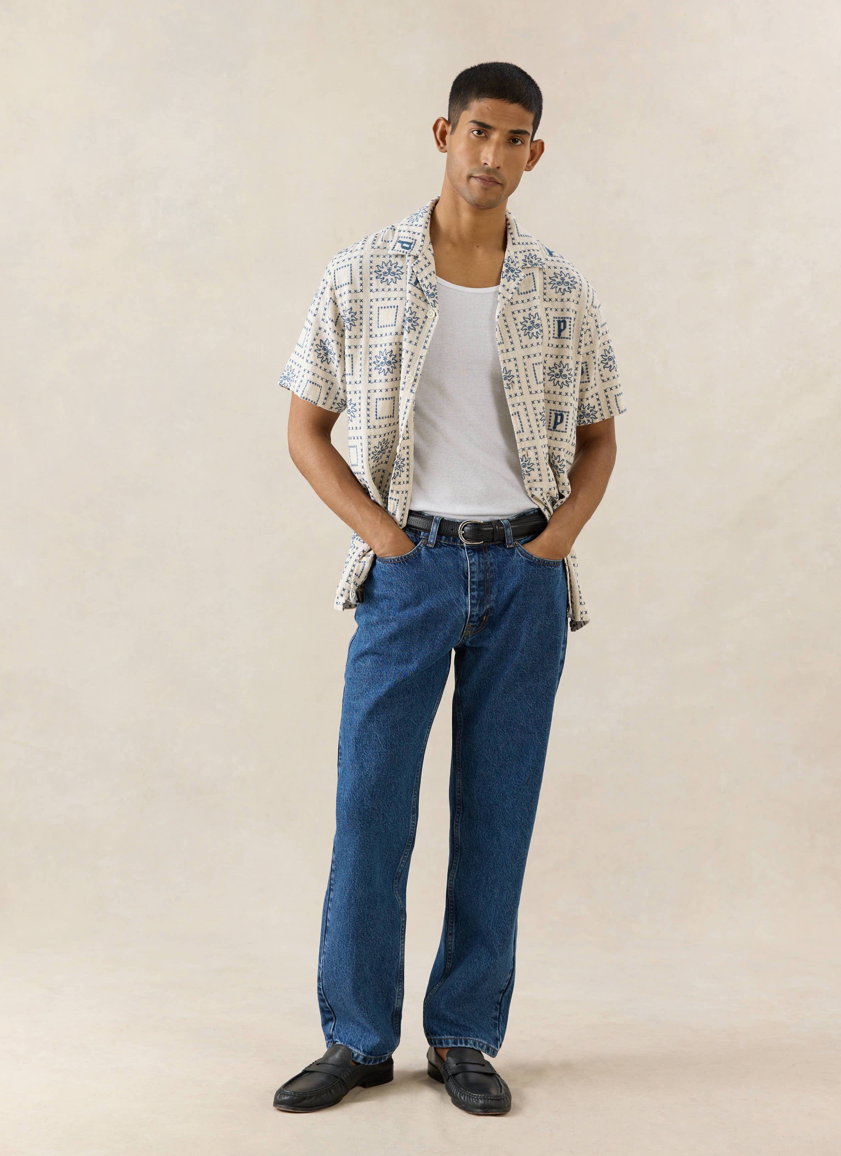 The Percival Solis Heaton Cuban Shirt in cream, a linen-blend short-sleeved shirt with blue embroidery on a model.