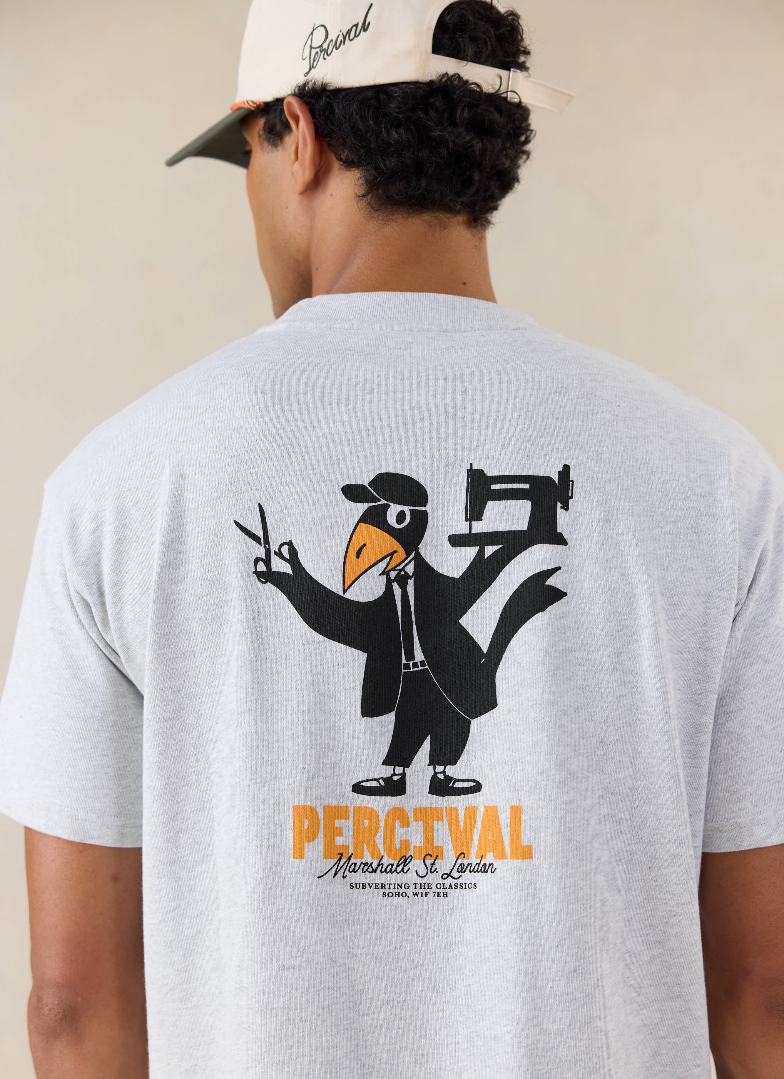 A model from behind wears the grey Atticus oversized T-shirt from Percival, highlighting the large back graphic print.