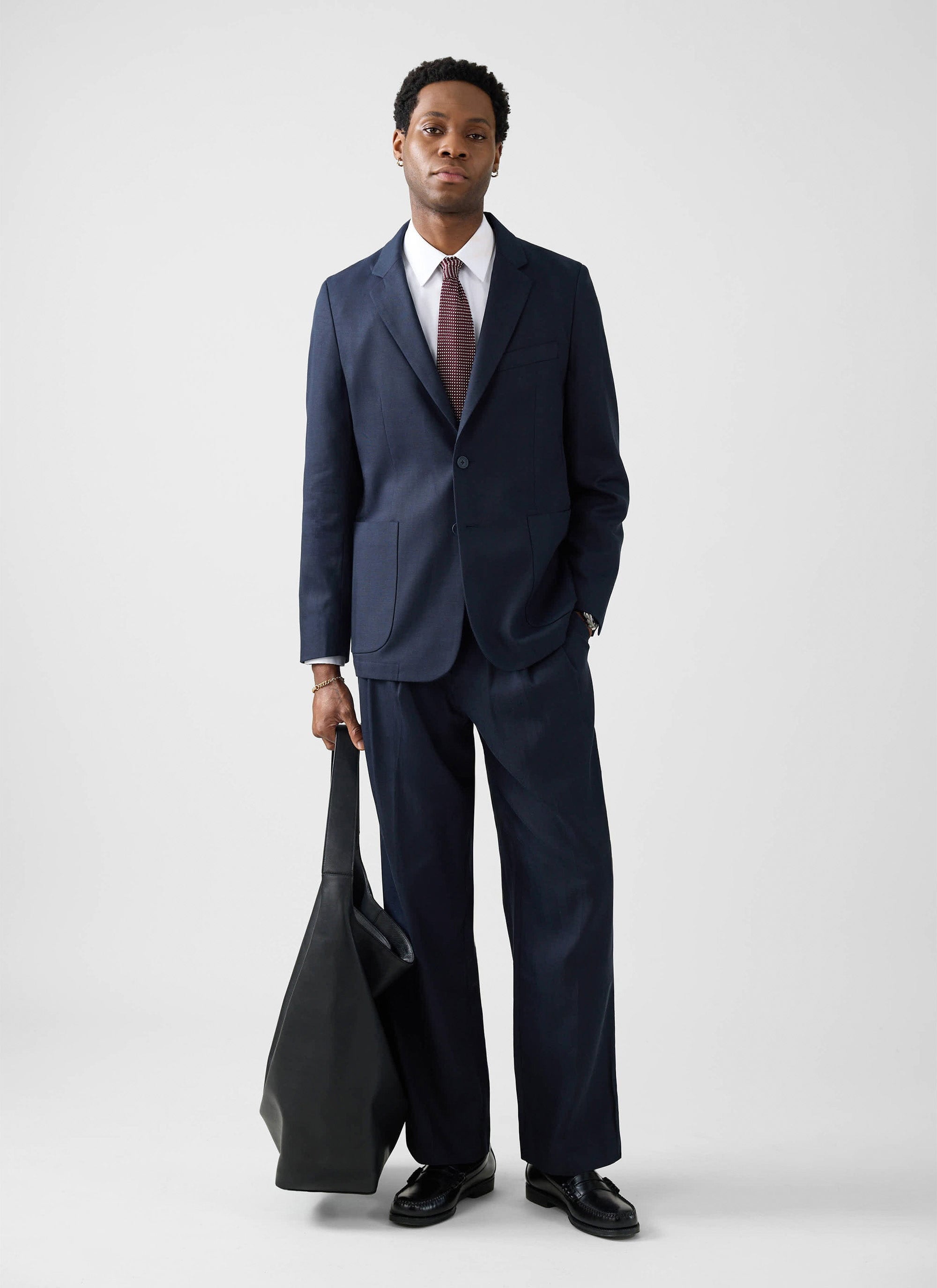 A model wears the navy Lyocell Regular Blazer and matching trousers from Percival, styled with a shirt and tie.